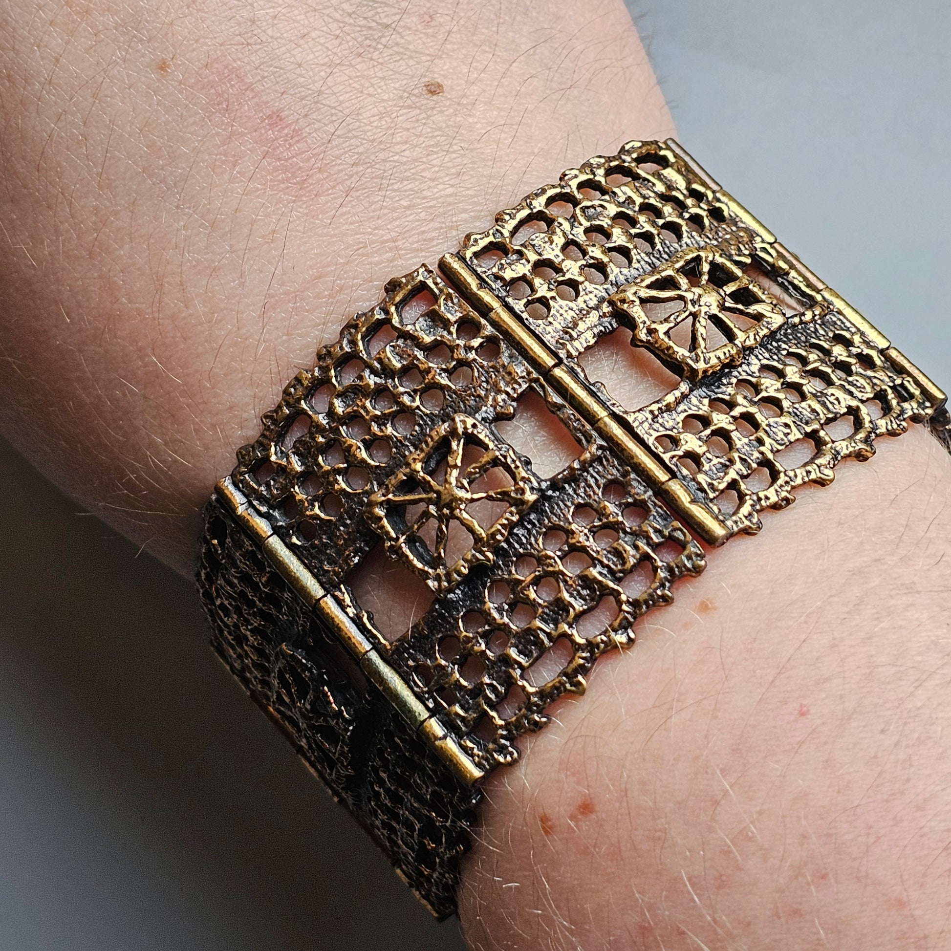 Ornate gold-toned filigree bracelet worn on a wrist.