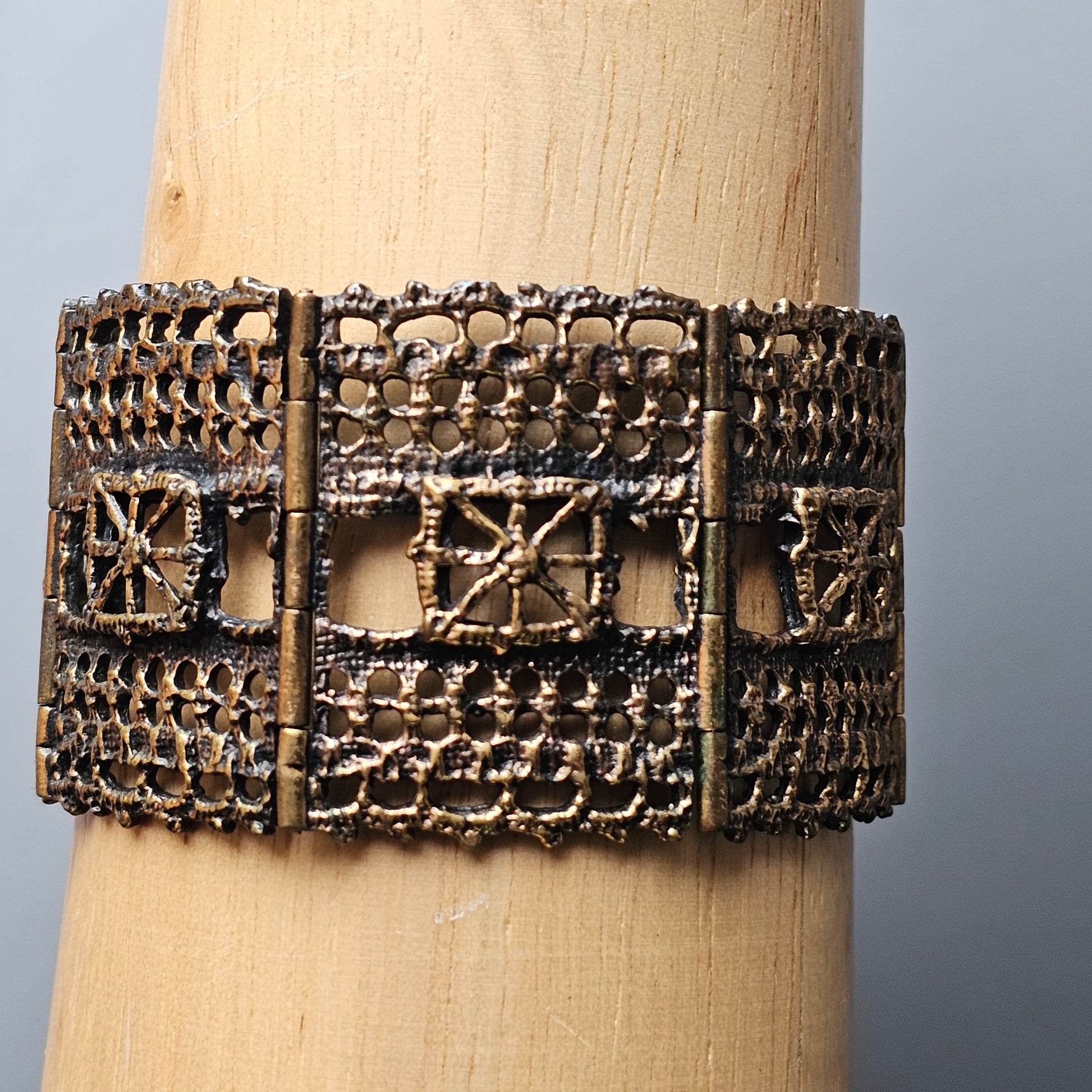 Ornate metallic cuff bracelet with intricate filigree patterns and geometric designs.