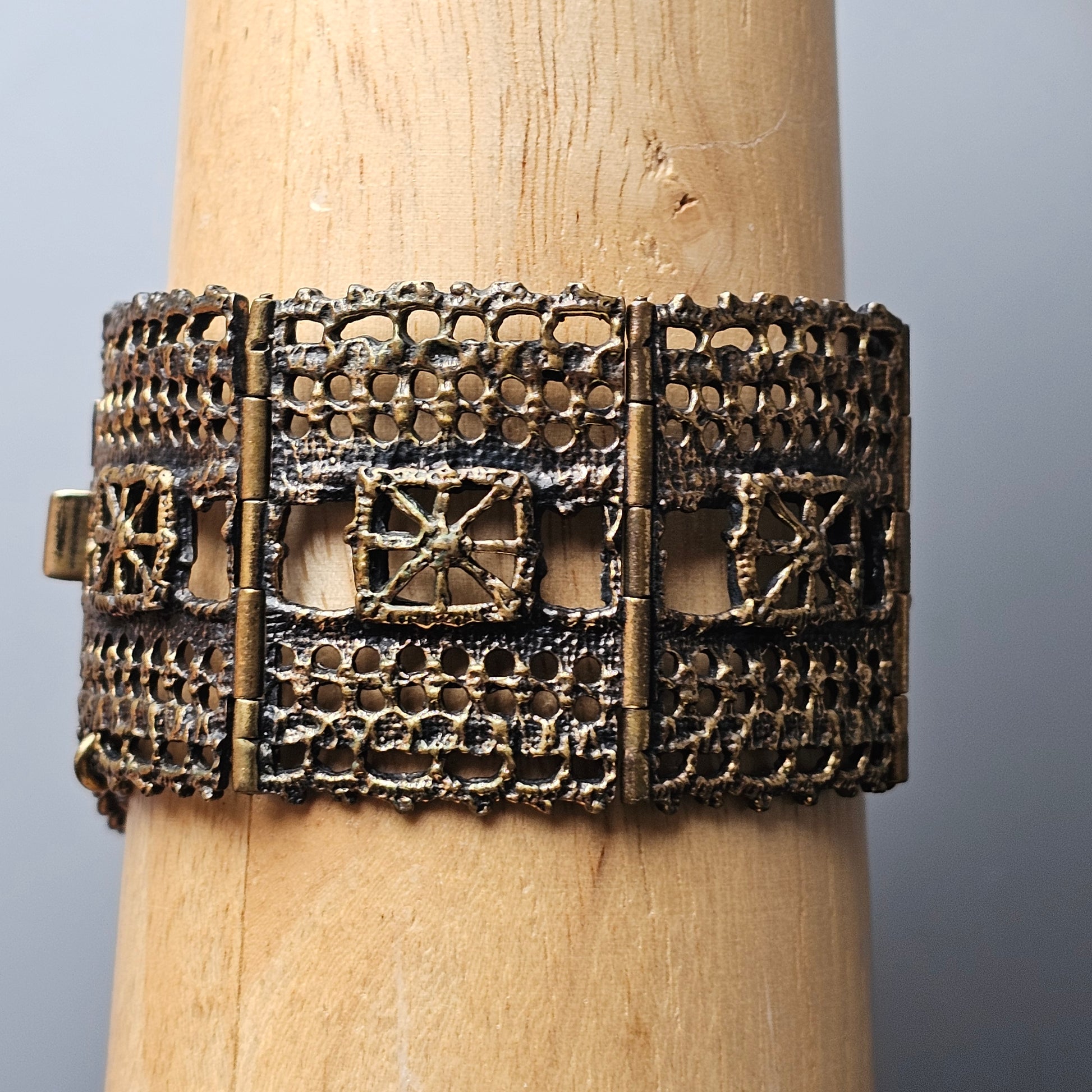 Ornate metallic bracelet with intricate geometric patterns and filigree work.