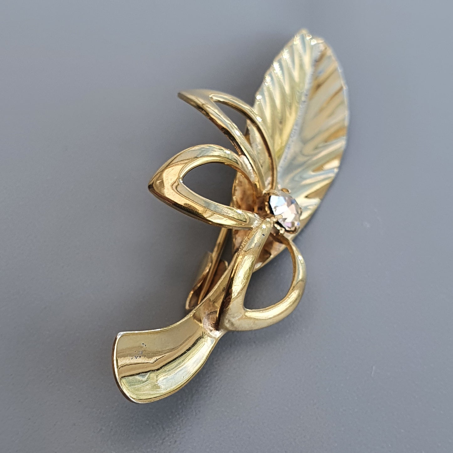 Gold-toned brooch or pin shaped like a stylized fairy or winged figure.