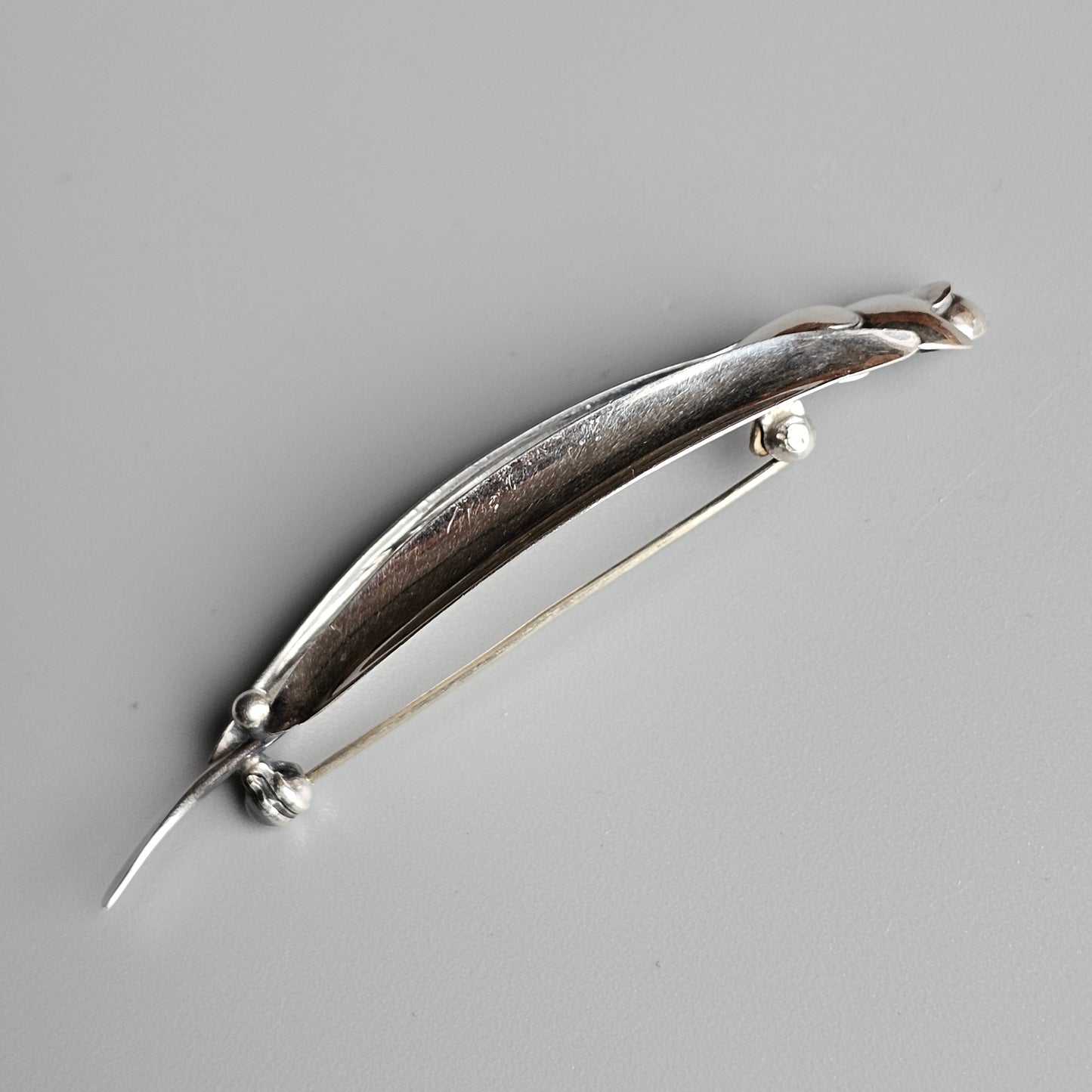 Silver brooch or pin shaped like an elongated fish or marine creature.