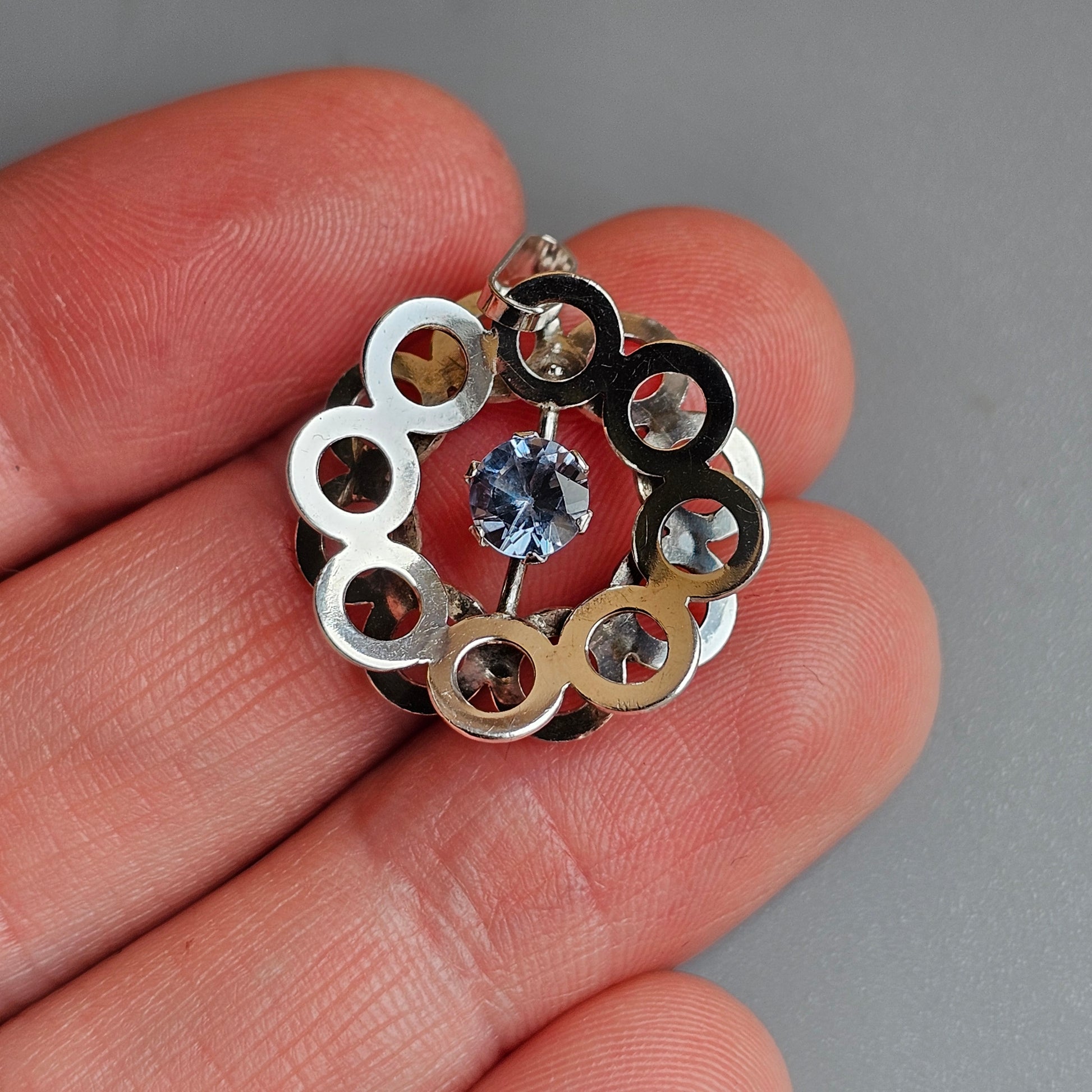 Circular pendant with metallic rings surrounding a central gemstone.