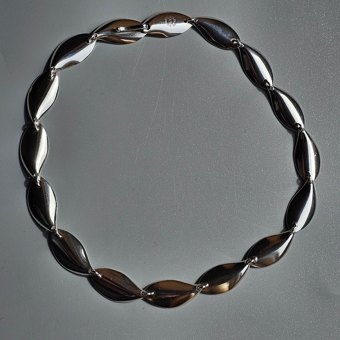 Silver necklace composed of oval-shaped links arranged in a circular form.