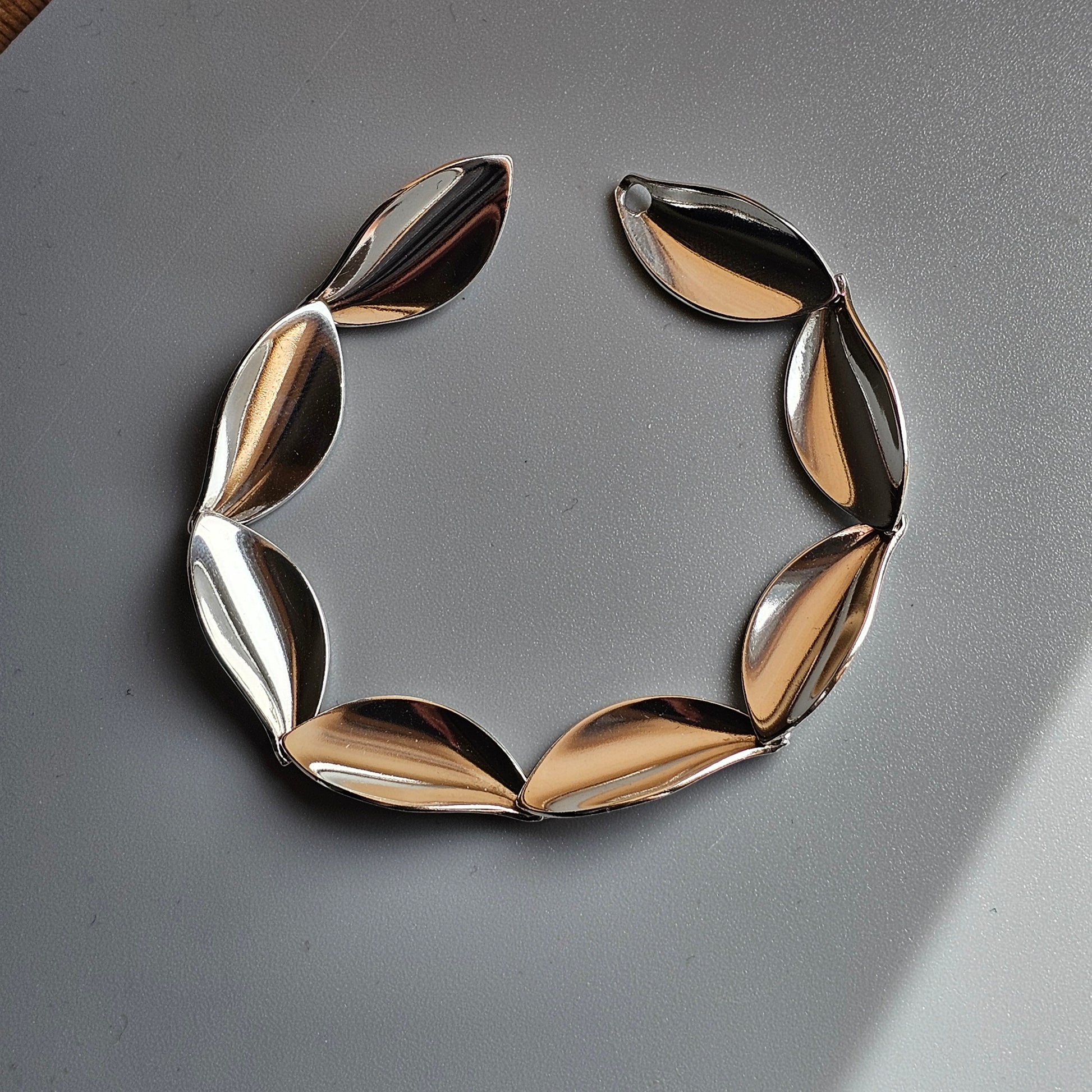 Metallic necklace or collar composed of curved, leaf-like segments arranged in a horseshoe shape.