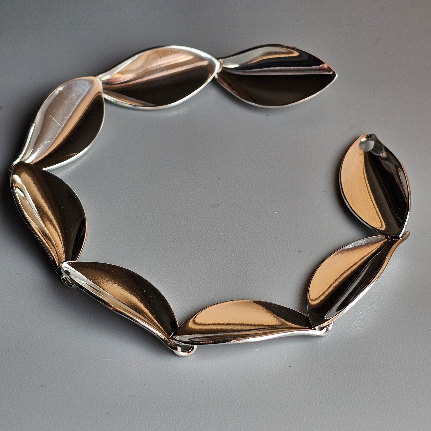 Stylish metallic bracelet with leaf-shaped links in gold and silver tones.