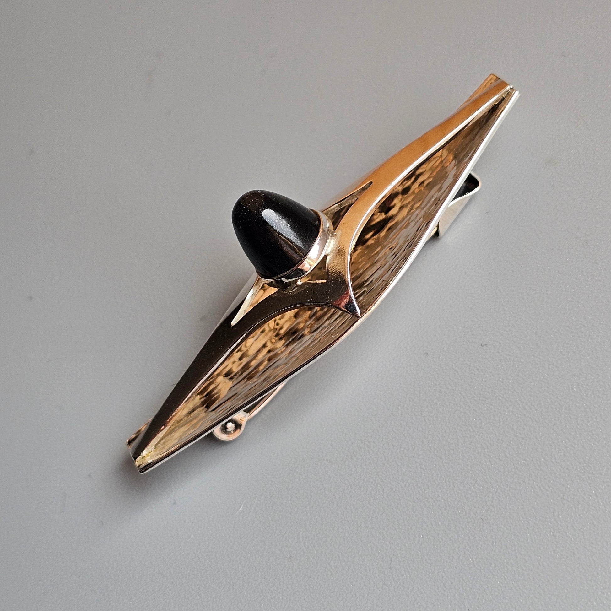 Vintage-style clothespin or clip with decorative wooden panels and a metal spring mechanism.