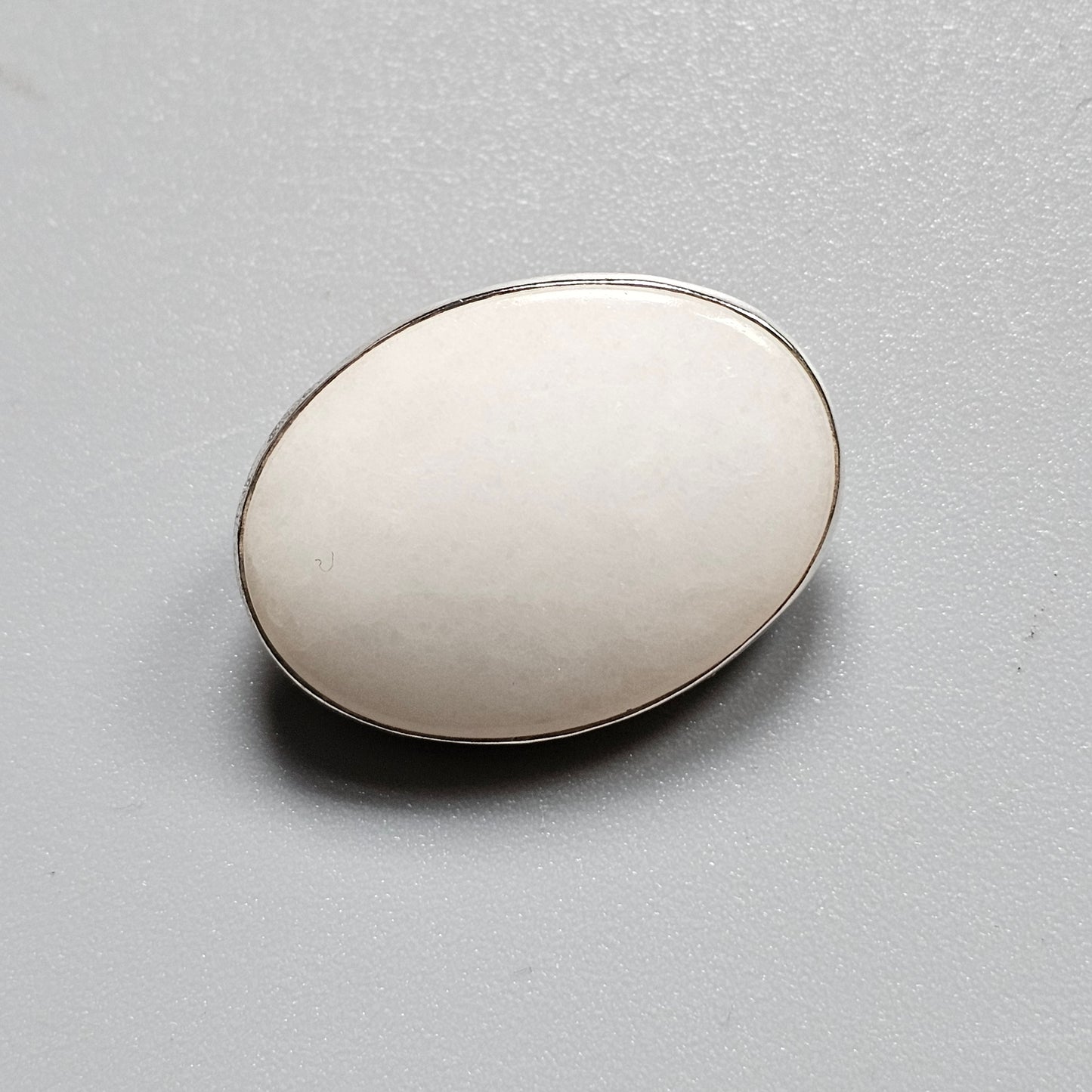 Smooth, oval-shaped white object with a metallic rim.