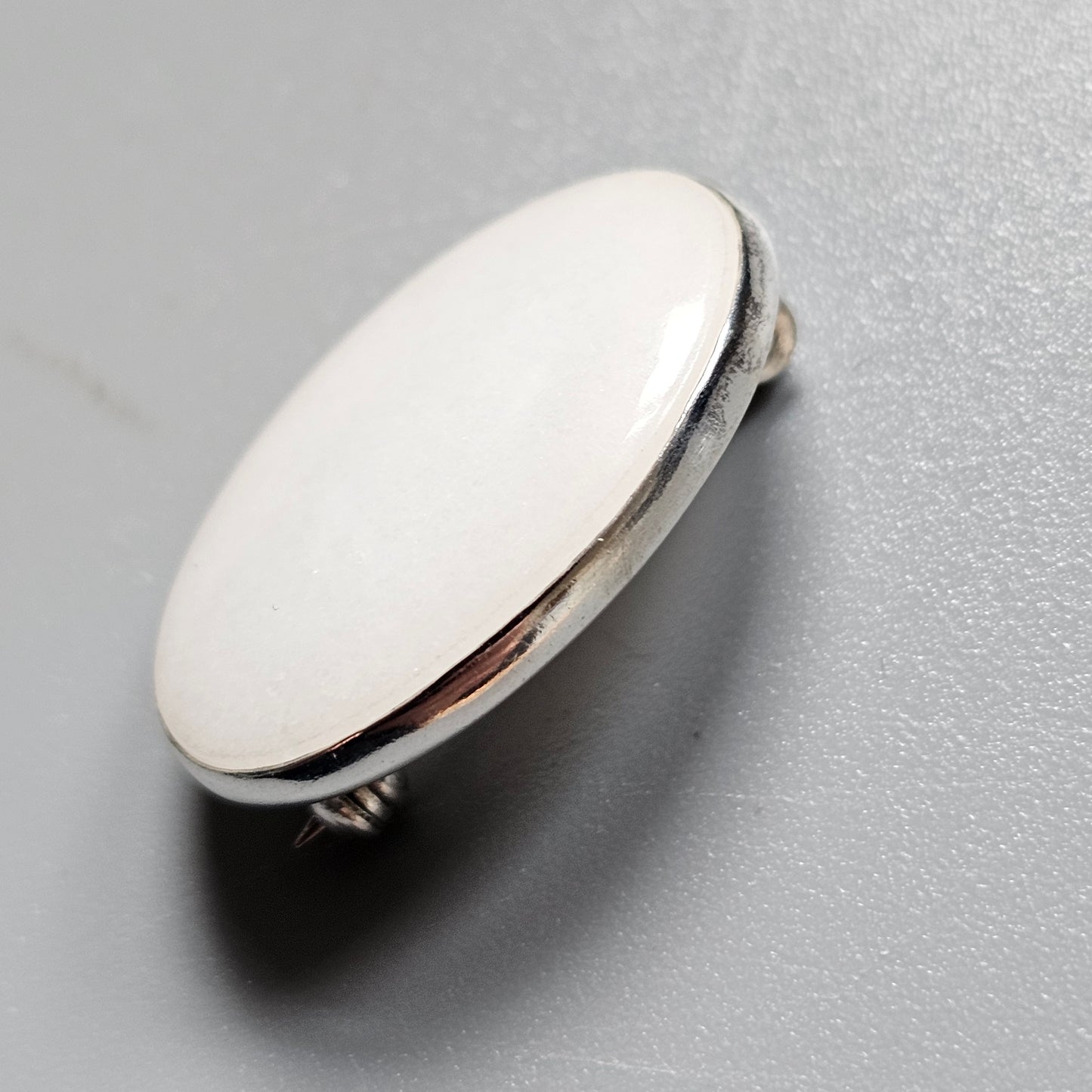 Shiny oval metal button or pin with a flat surface.