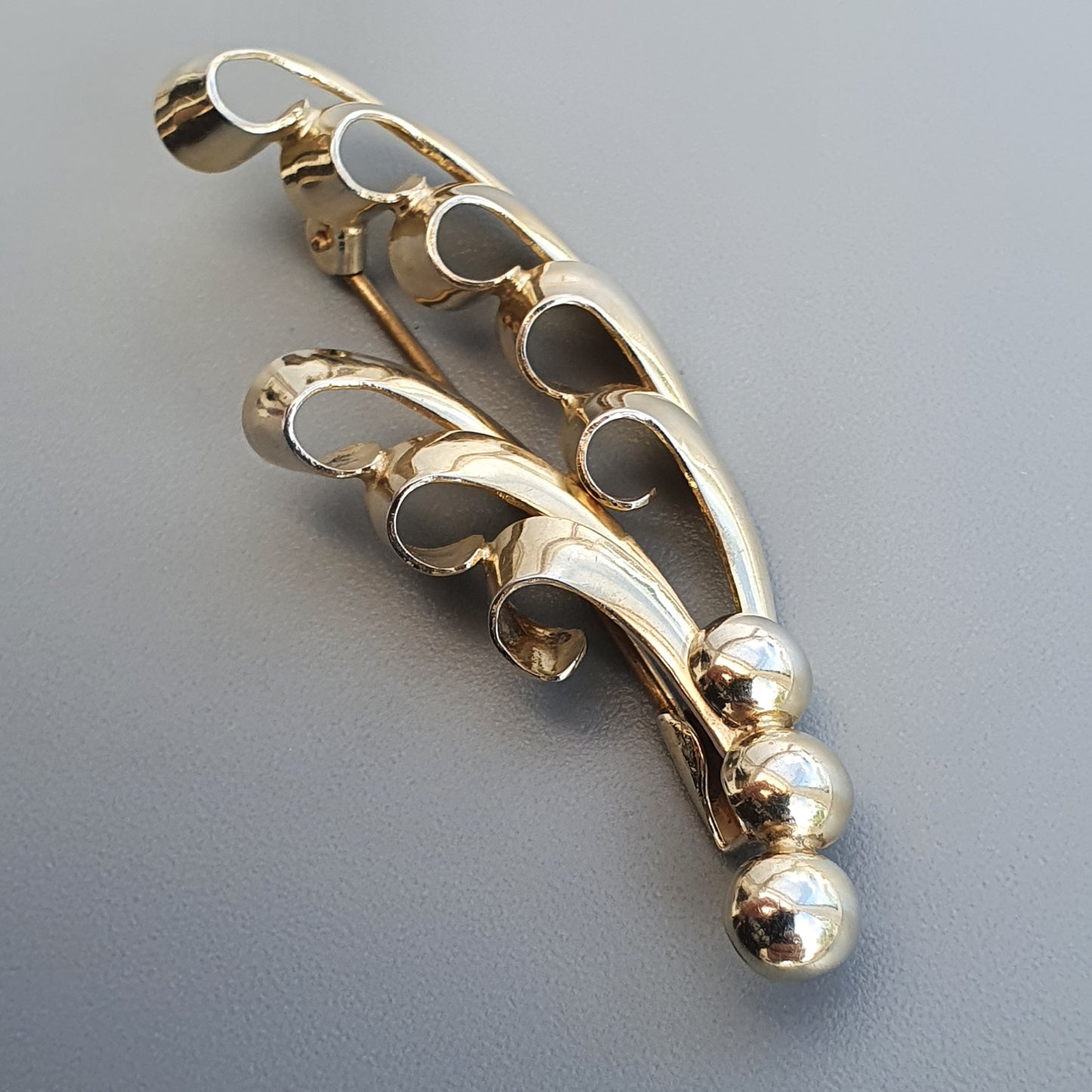 Gold-toned metal knuckle duster or brass knuckles with decorative cutout design.