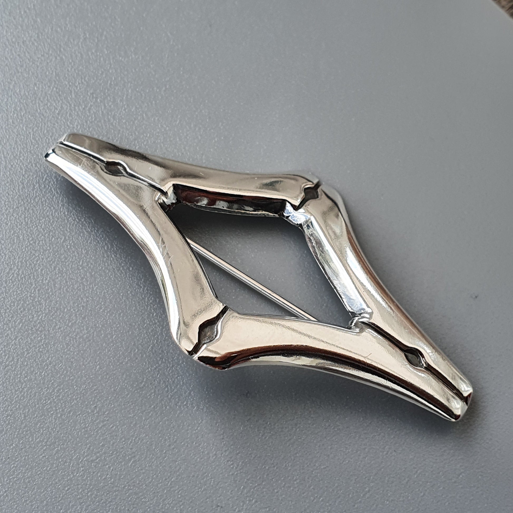 Diamond-shaped metal locking pliers or clamp tool.