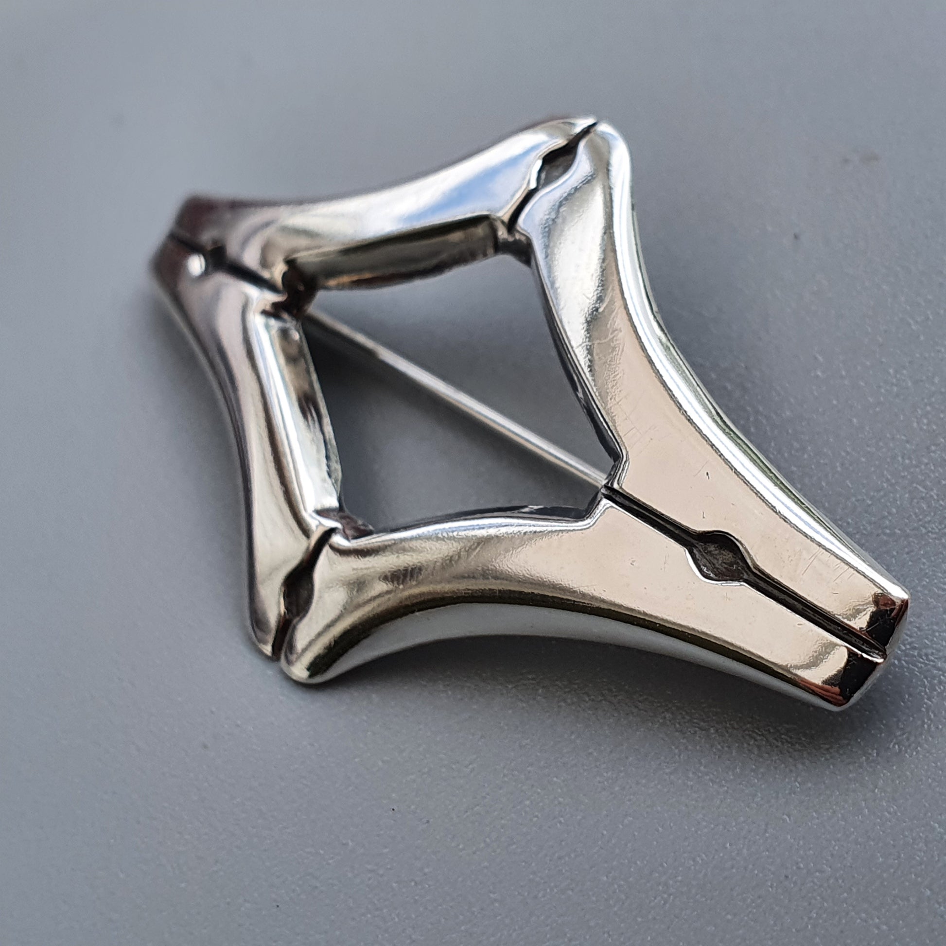 Metallic star-shaped pendant or brooch with a geometric design.