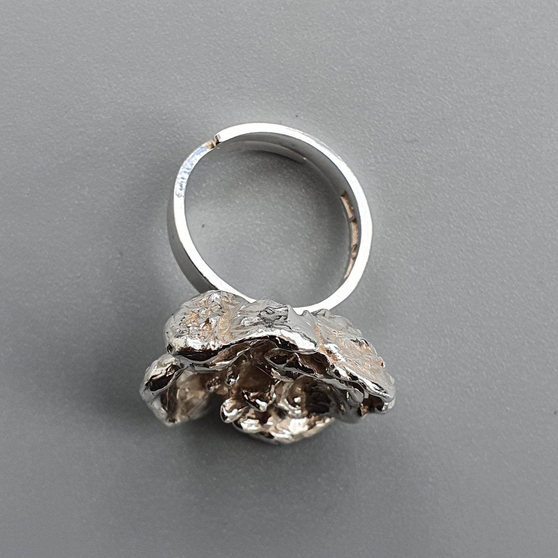 Unique silver ring featuring an organic, textured floral or coral-like design as its centerpiece.