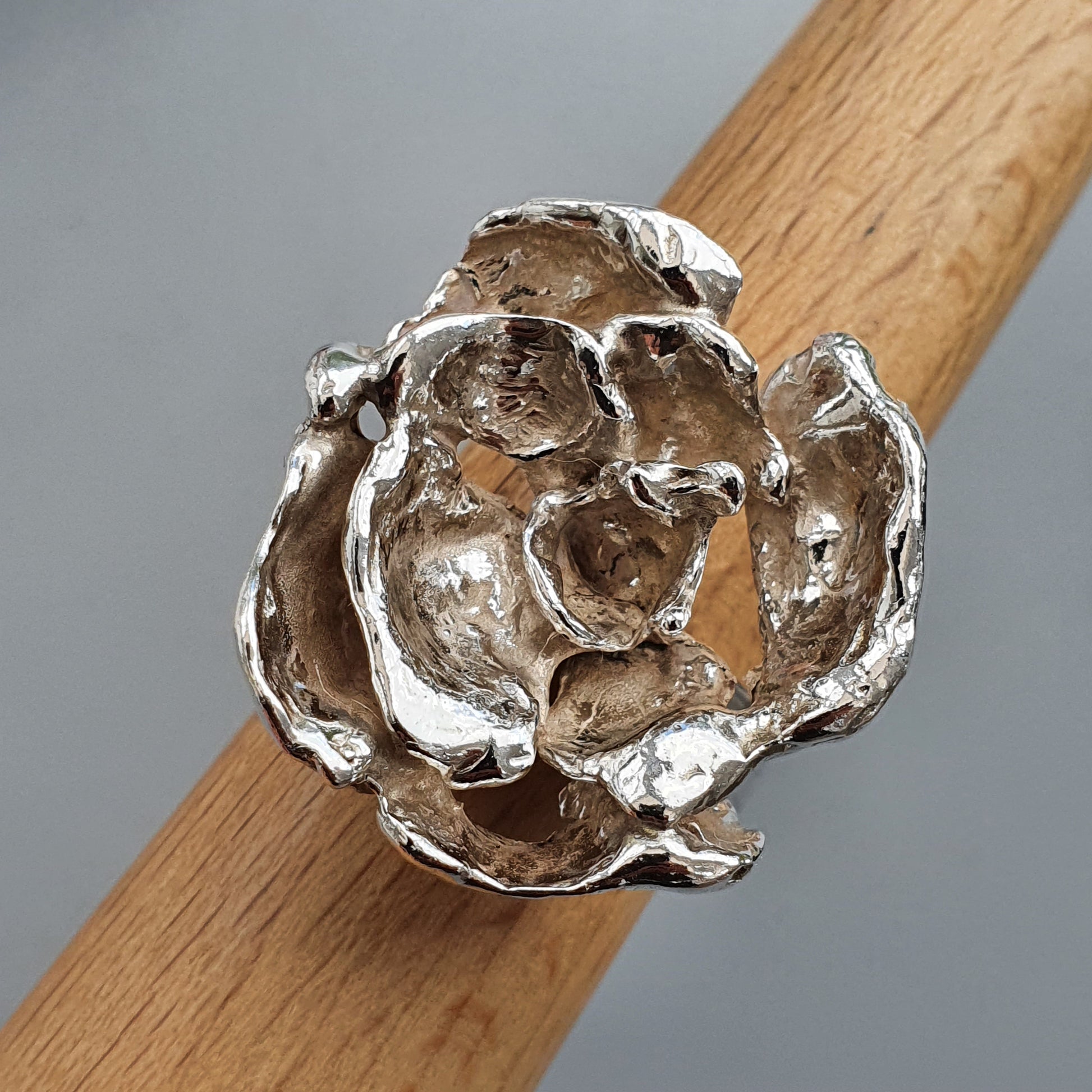 Silver rose-shaped ring with textured petals.