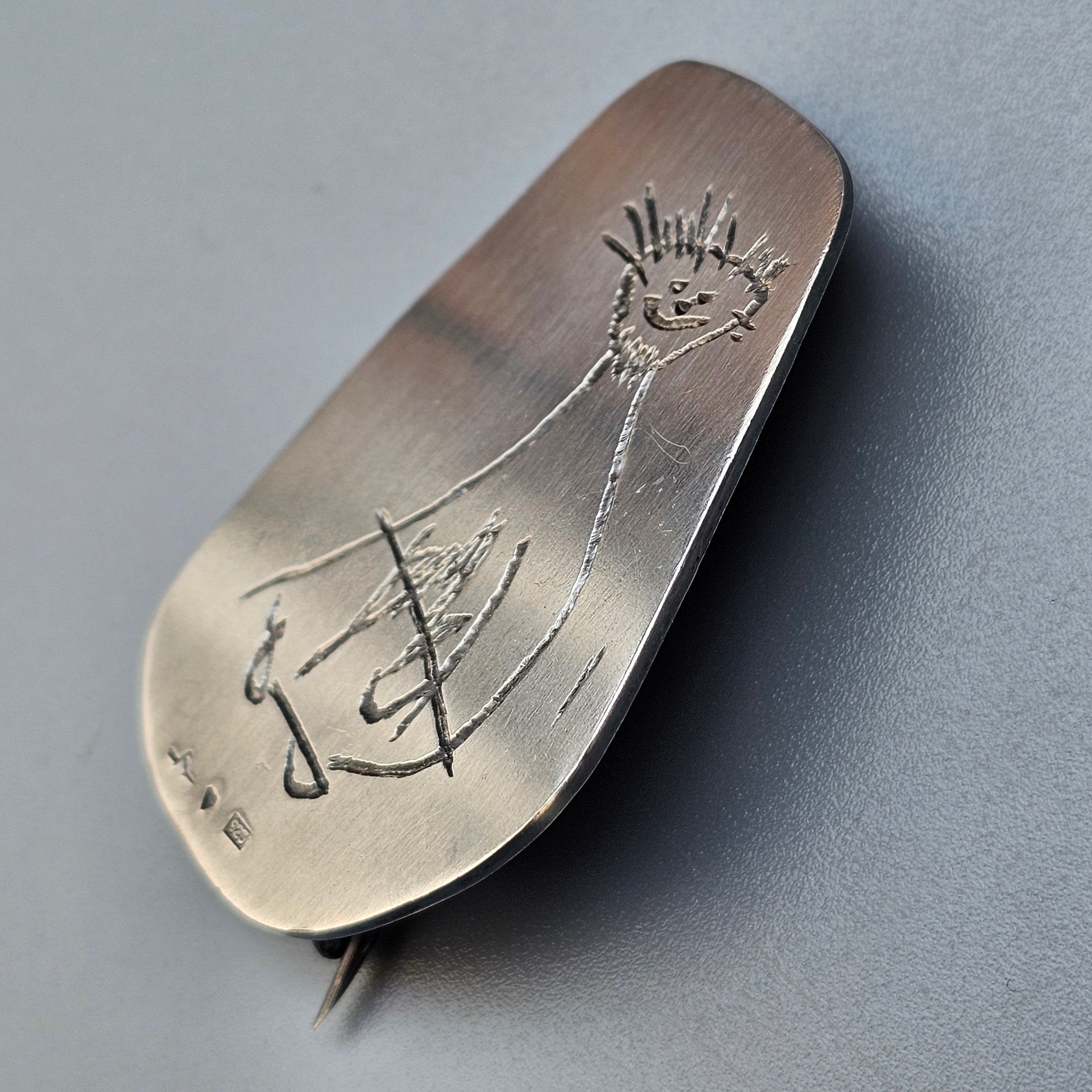 Silver spoon with an engraved childlike drawing of a stick figure.