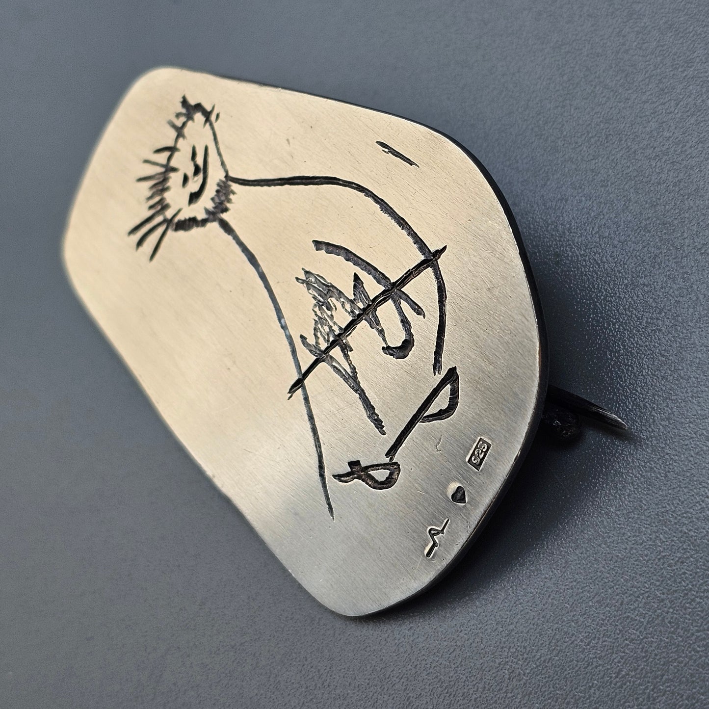 Guitar pick with a simple sketch of a guitar-playing figure drawn on it.