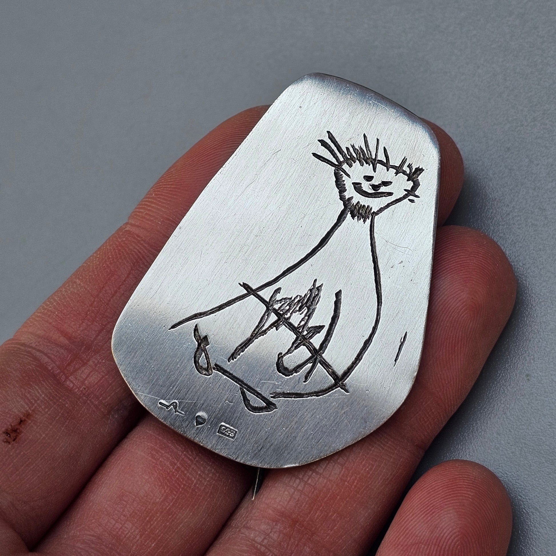 Metal pendant with a simple engraved bird design.