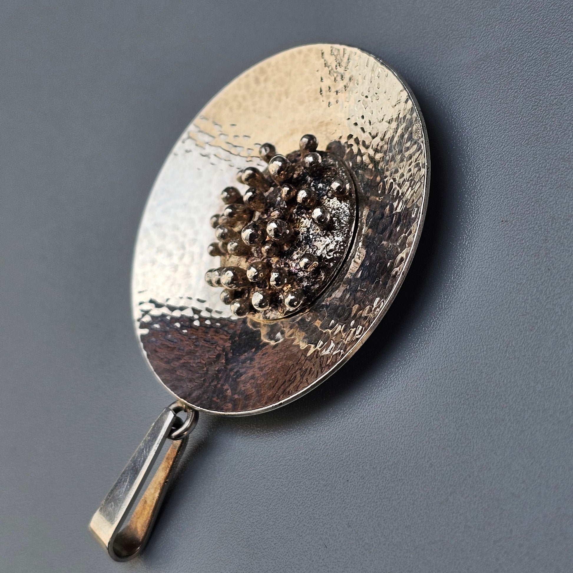 Metal slotted spoon containing black peppercorns.