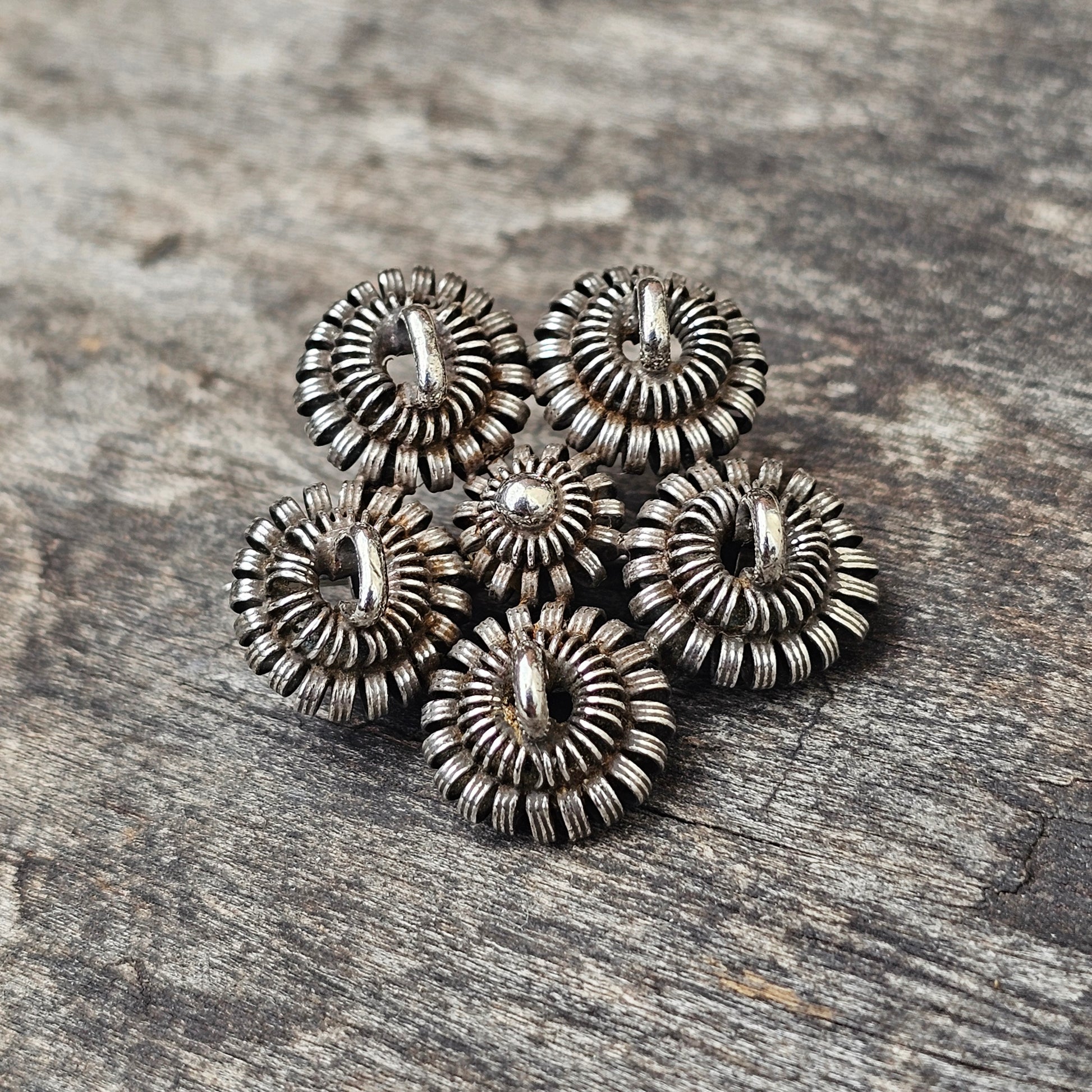 Cluster of six ornate, silver-toned metal buttons with a sunburst or floral design.