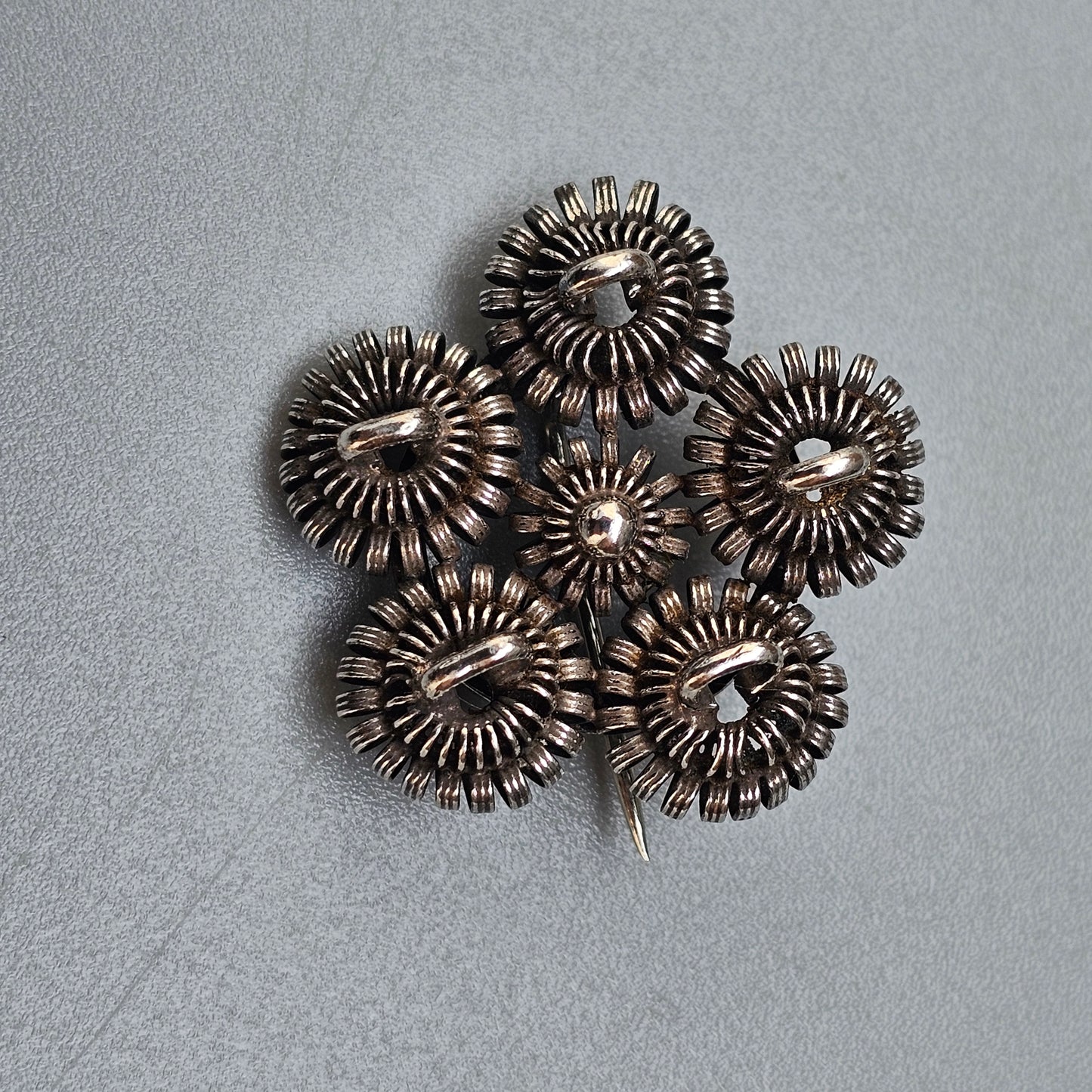 Metallic flower-shaped brooch or ornament with circular petal-like components.