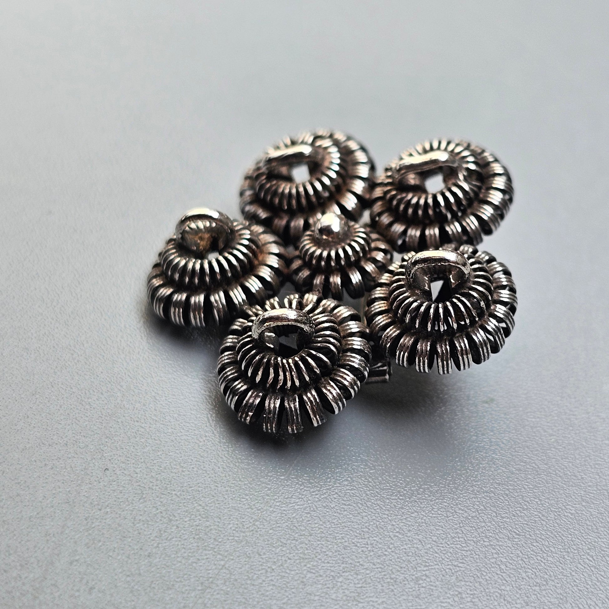 Metallic spiral-shaped beads or spacers clustered together.