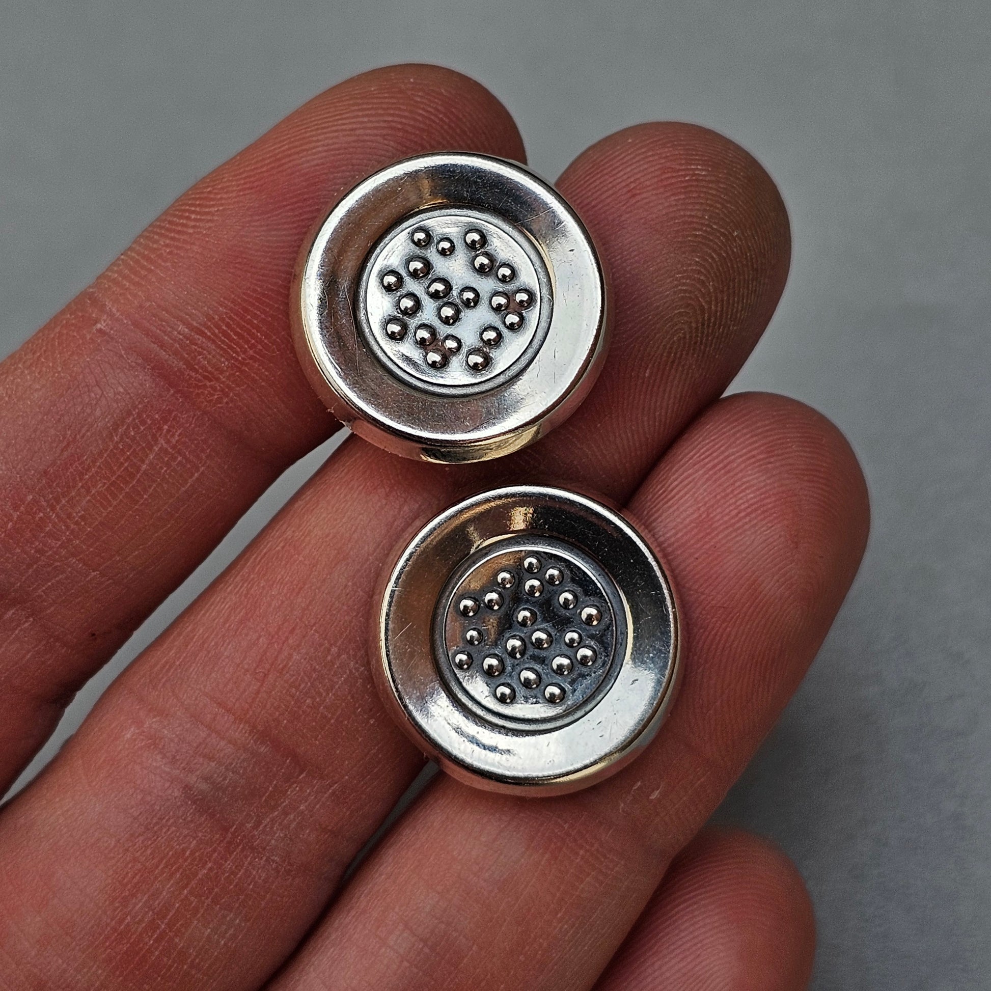 Two circular metal components with small ball bearings inside.