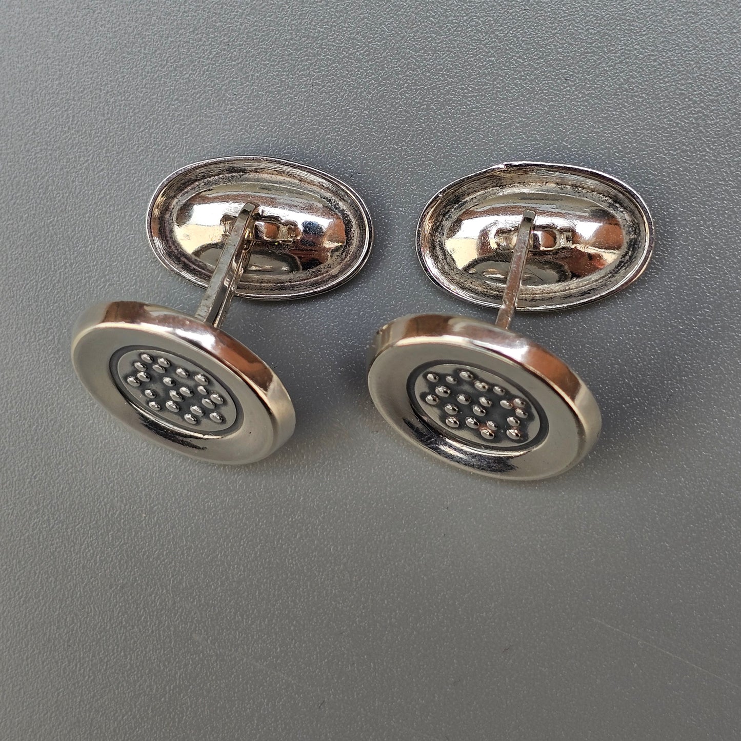 Pair of silver cufflinks with circular faces featuring a dotted pattern.