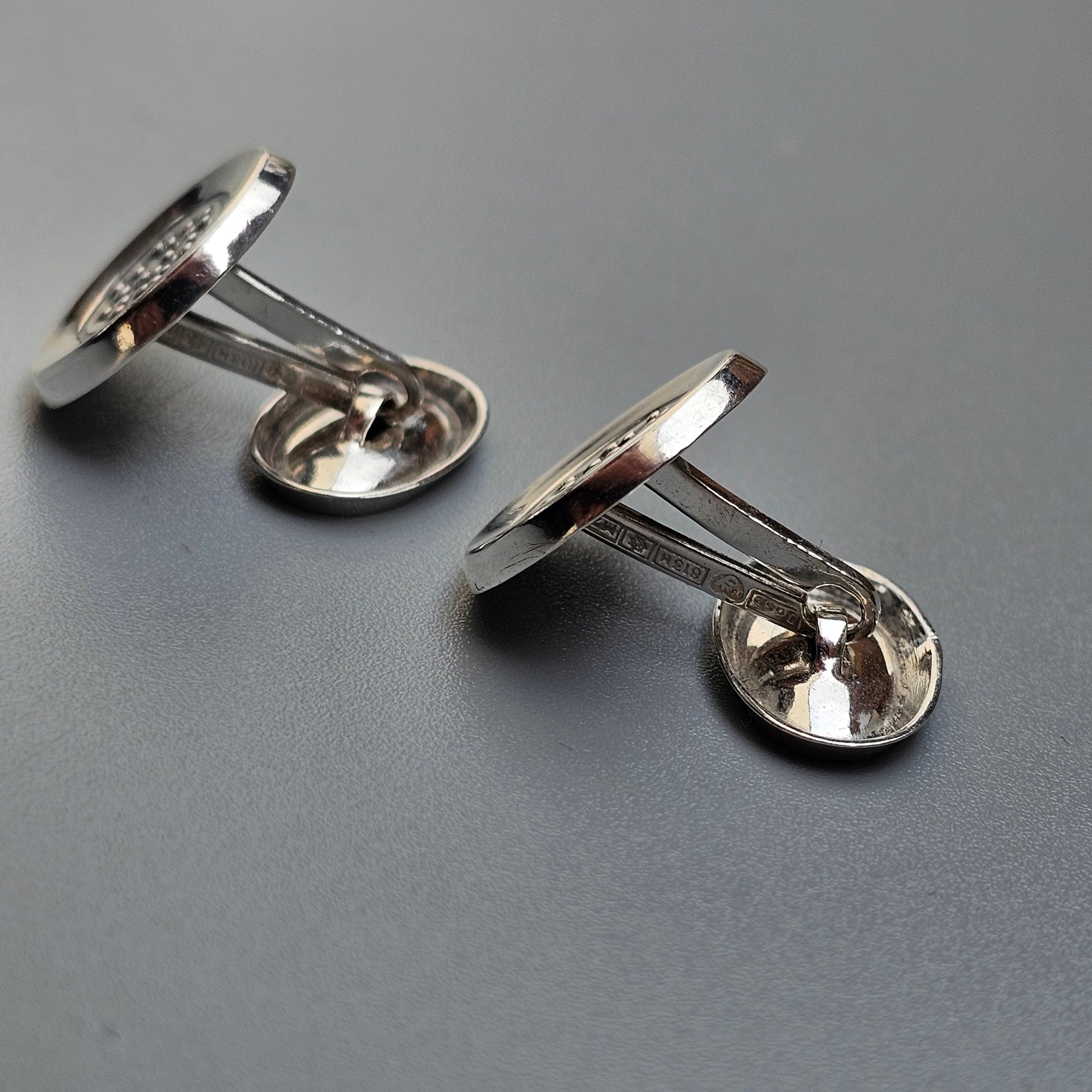 Pair of silver-colored metal cufflinks with round faces.