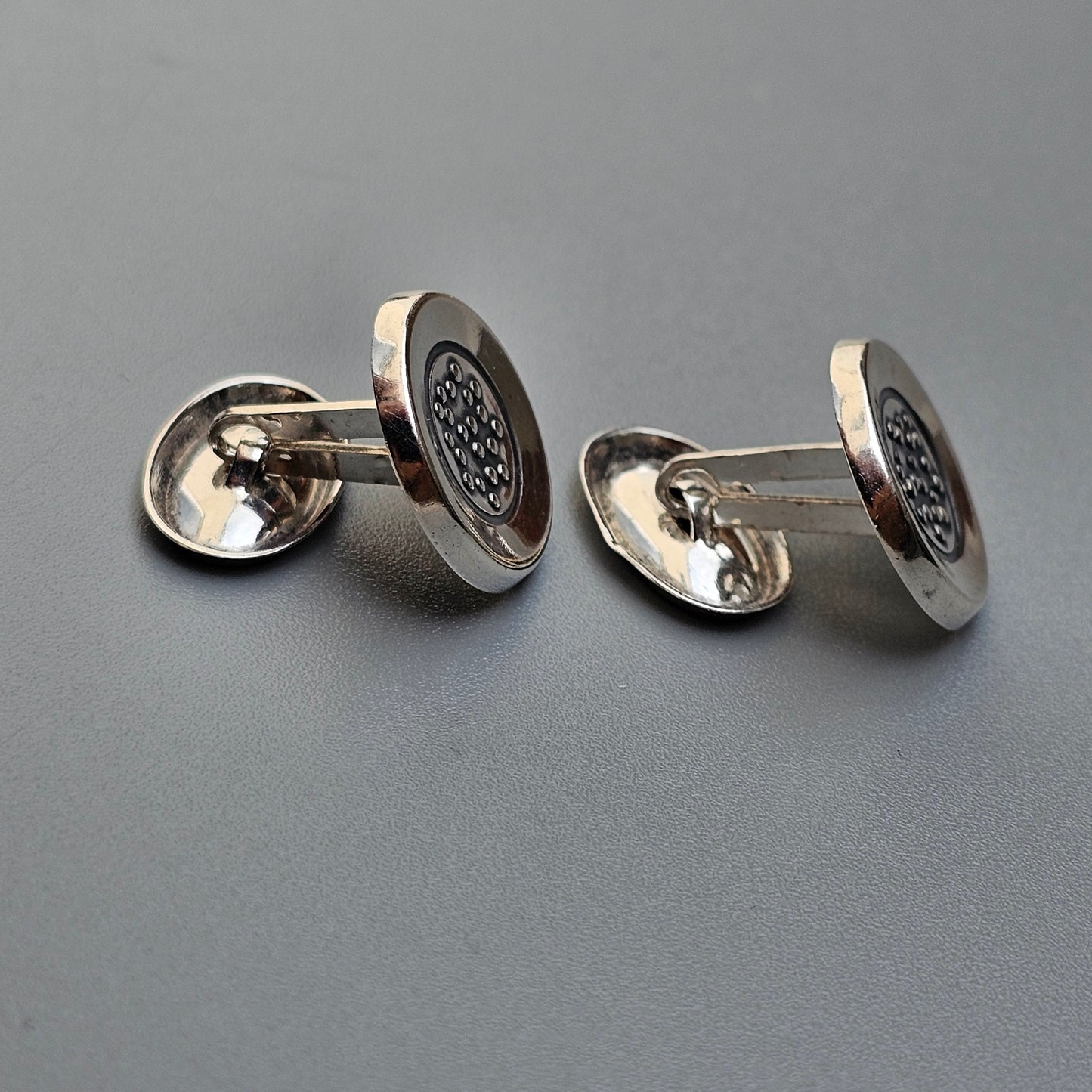 Pair of silver cufflinks with circular faces featuring a textured pattern.