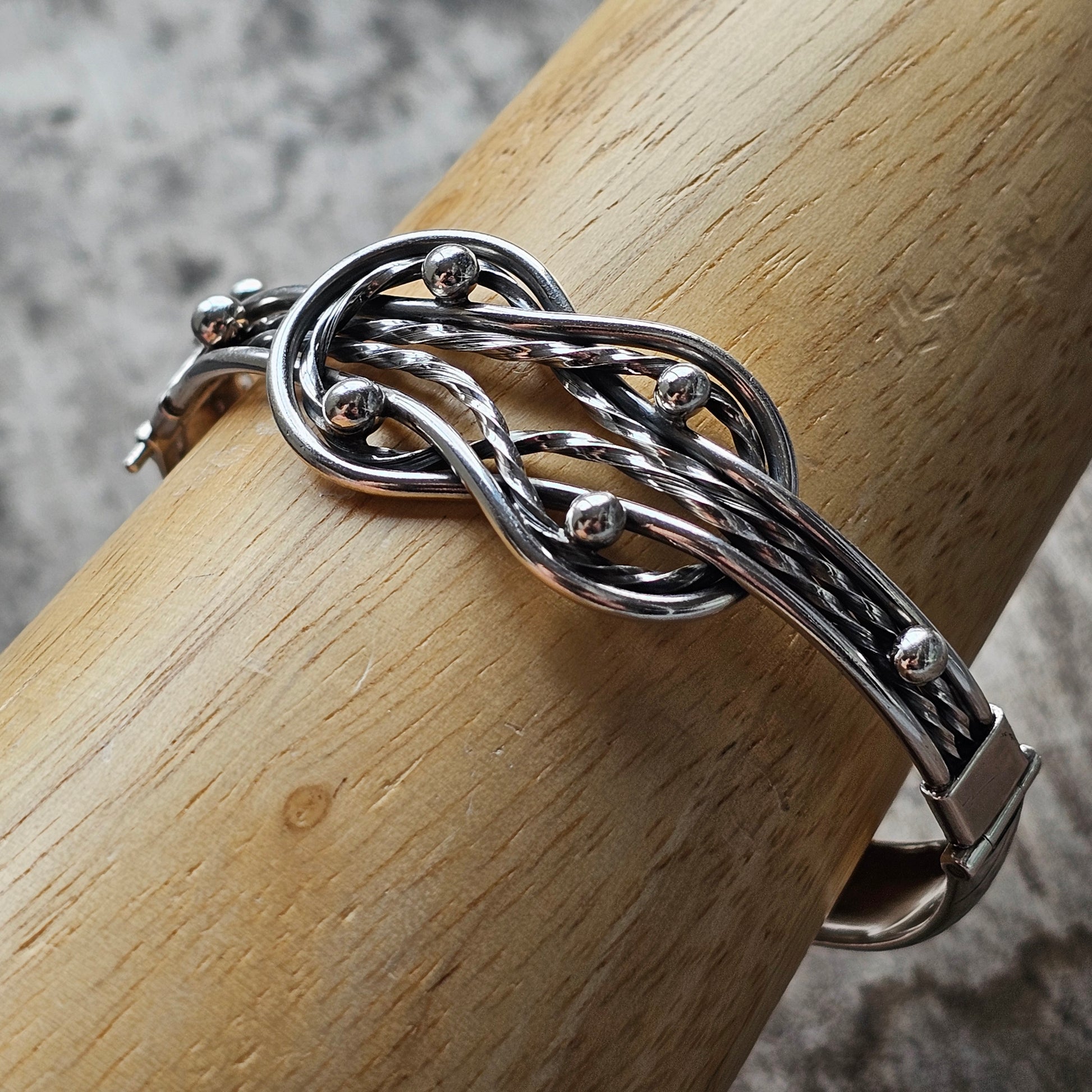 Silver bracelet with an intricate knot design.