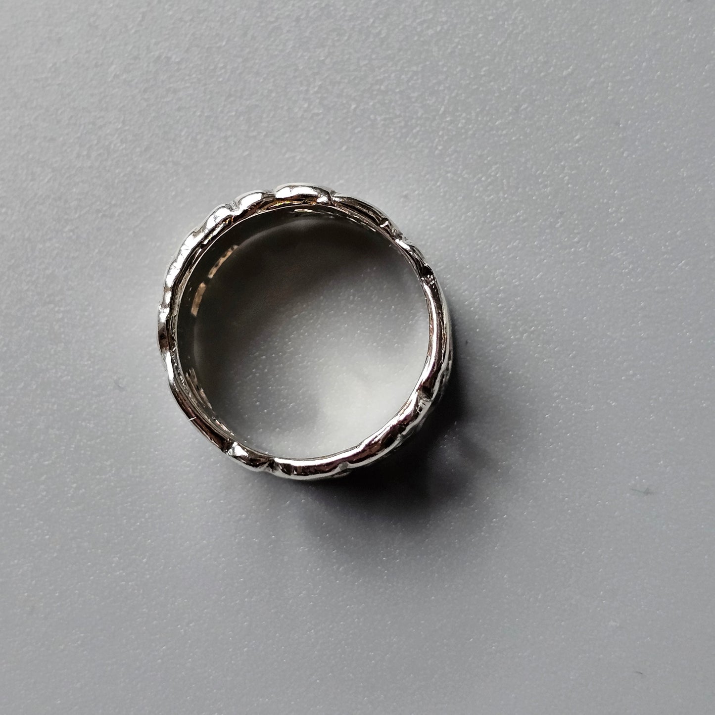 Silver ring with a textured, branch-like design around its circumference.