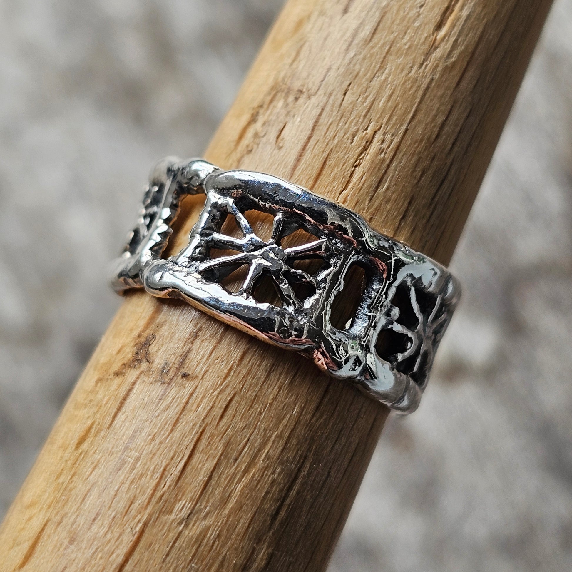 Silver ring with a cross pattern and ornate detailing.