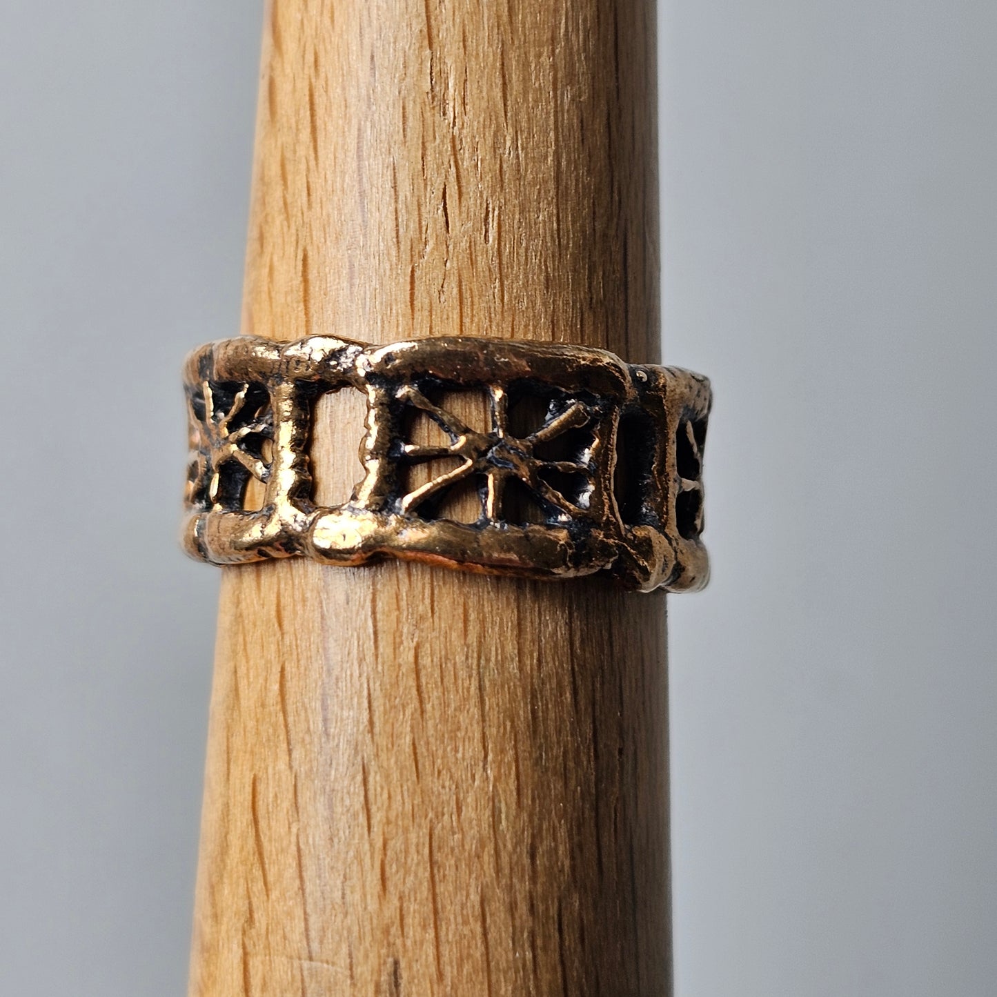 Ornate metal ring with a floral or star-like pattern encircling a wooden cylinder.