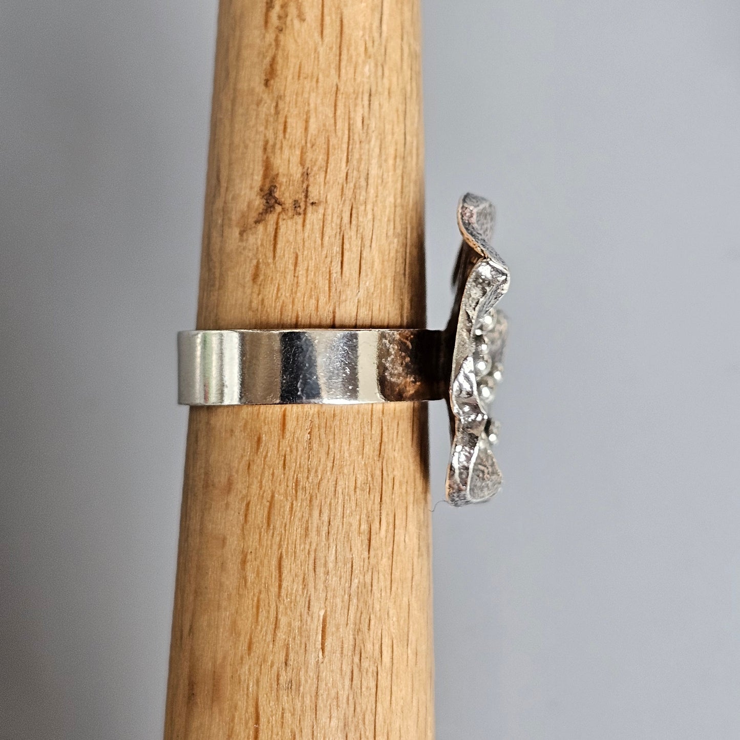 Silver ring with a textured, wing-like extension on one side.