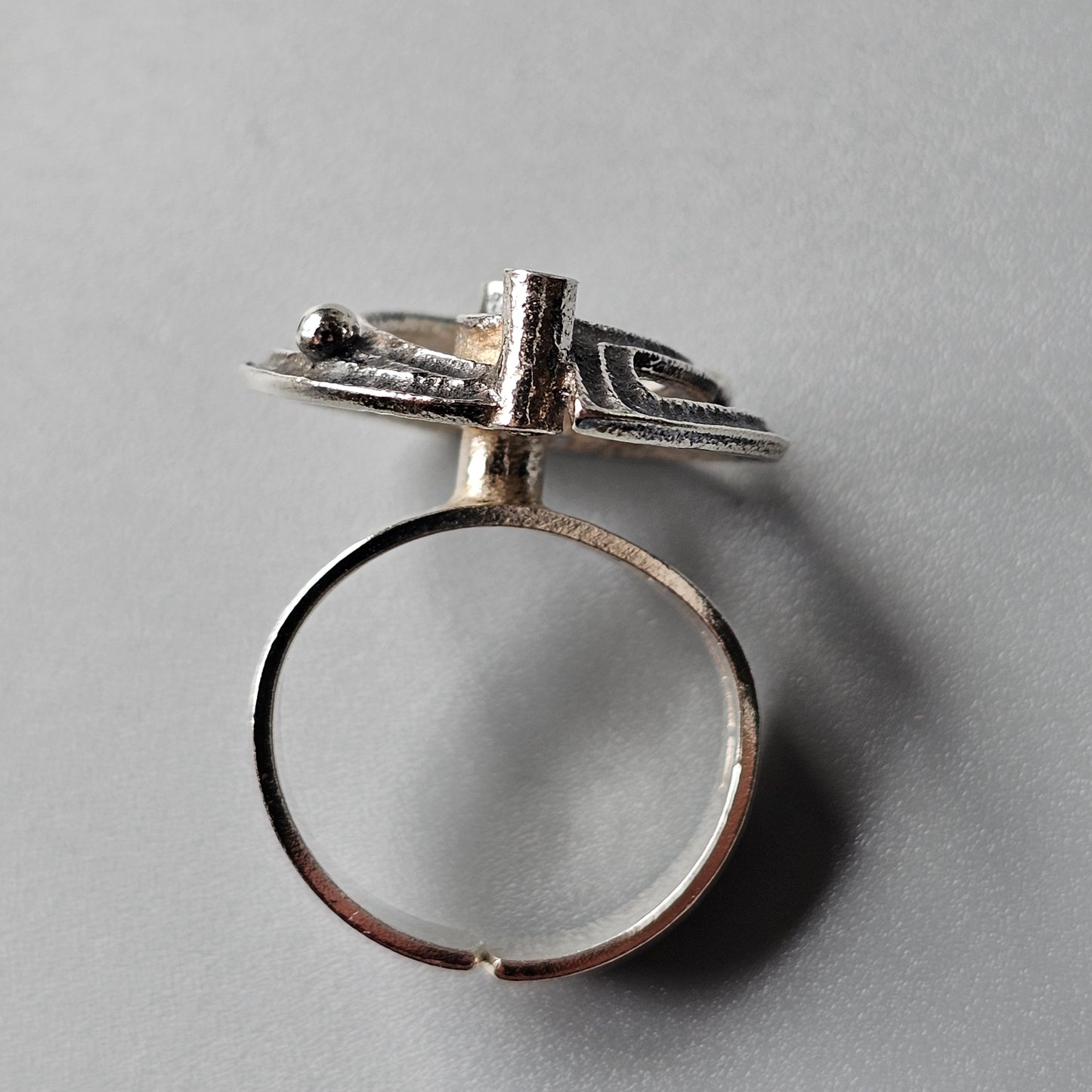 Silver ring featuring a stylized bird or airplane design on top.