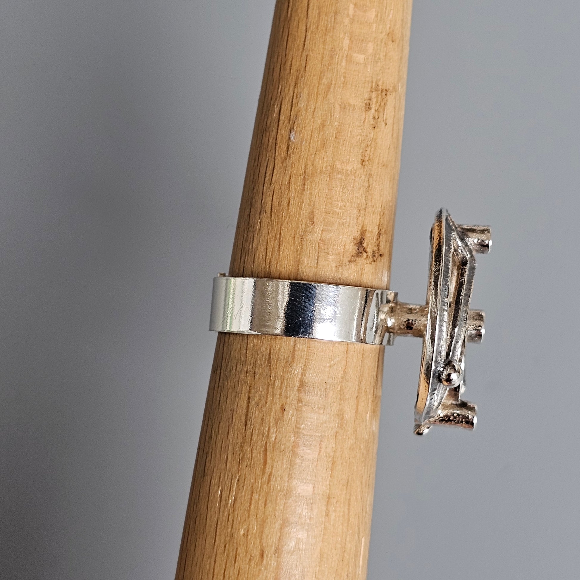 Silver ring with a miniature airplane charm attached to the band.