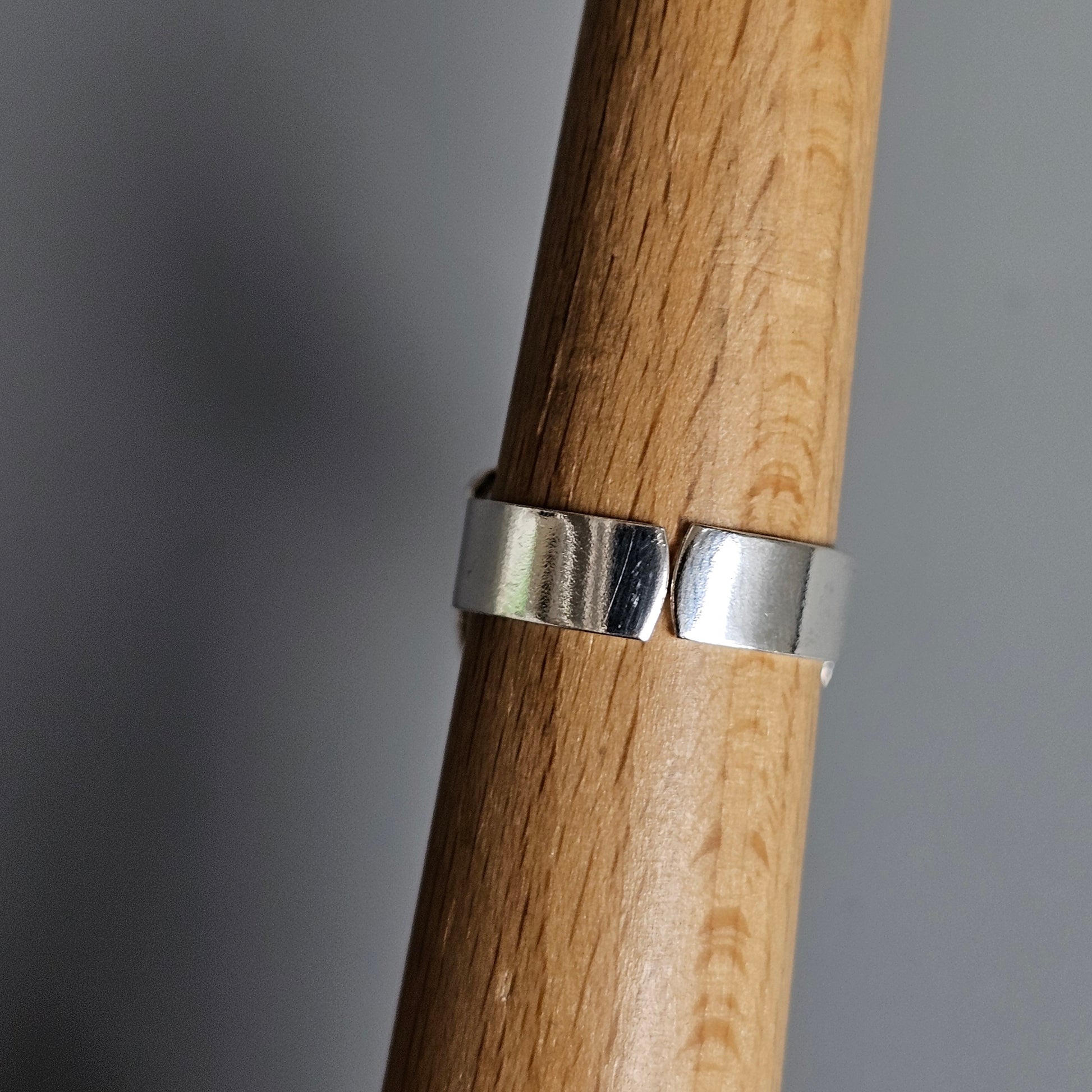 Wooden dowel or rod with a silver metal band wrapped around it.