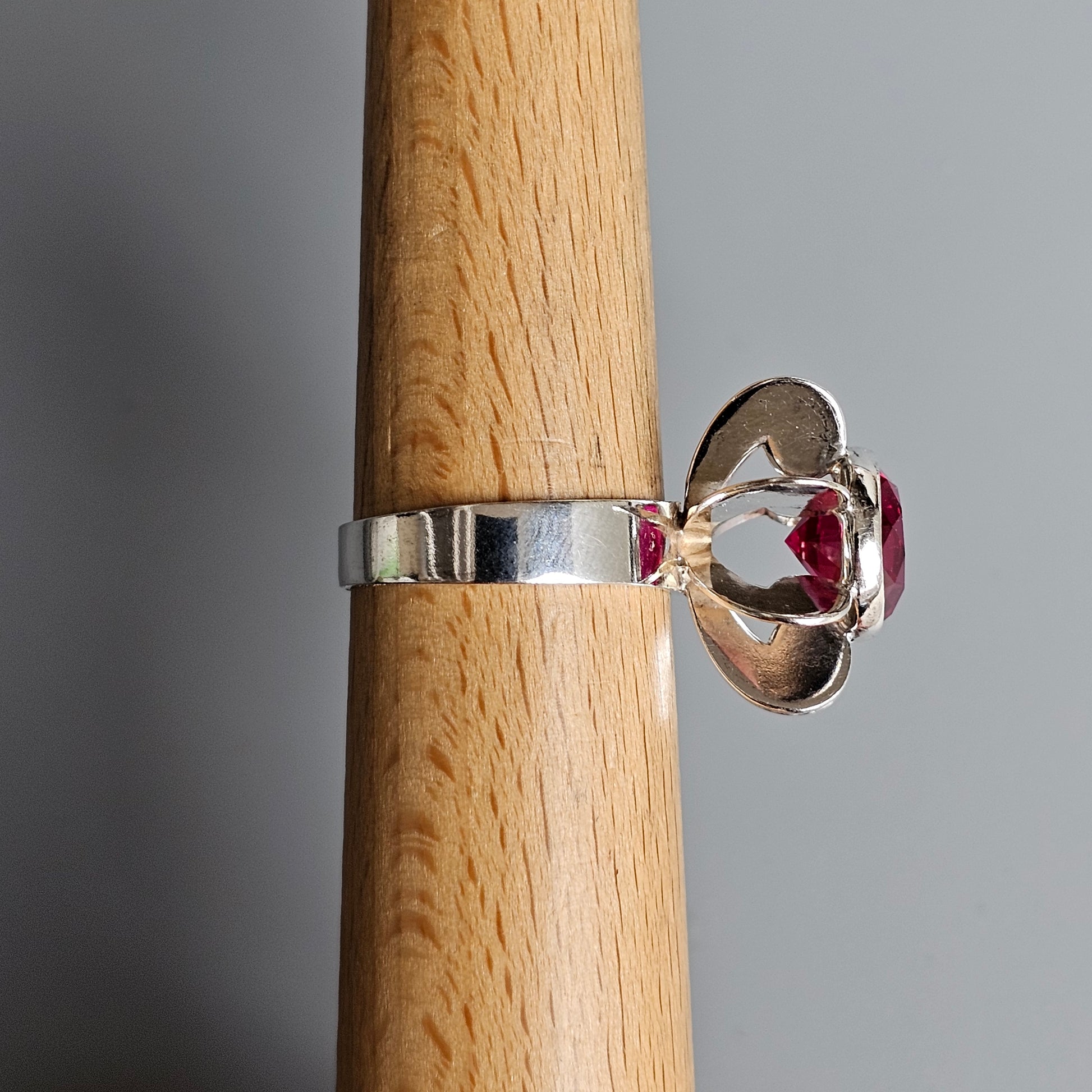 Silver ring with a prominent red gemstone in a raised setting.