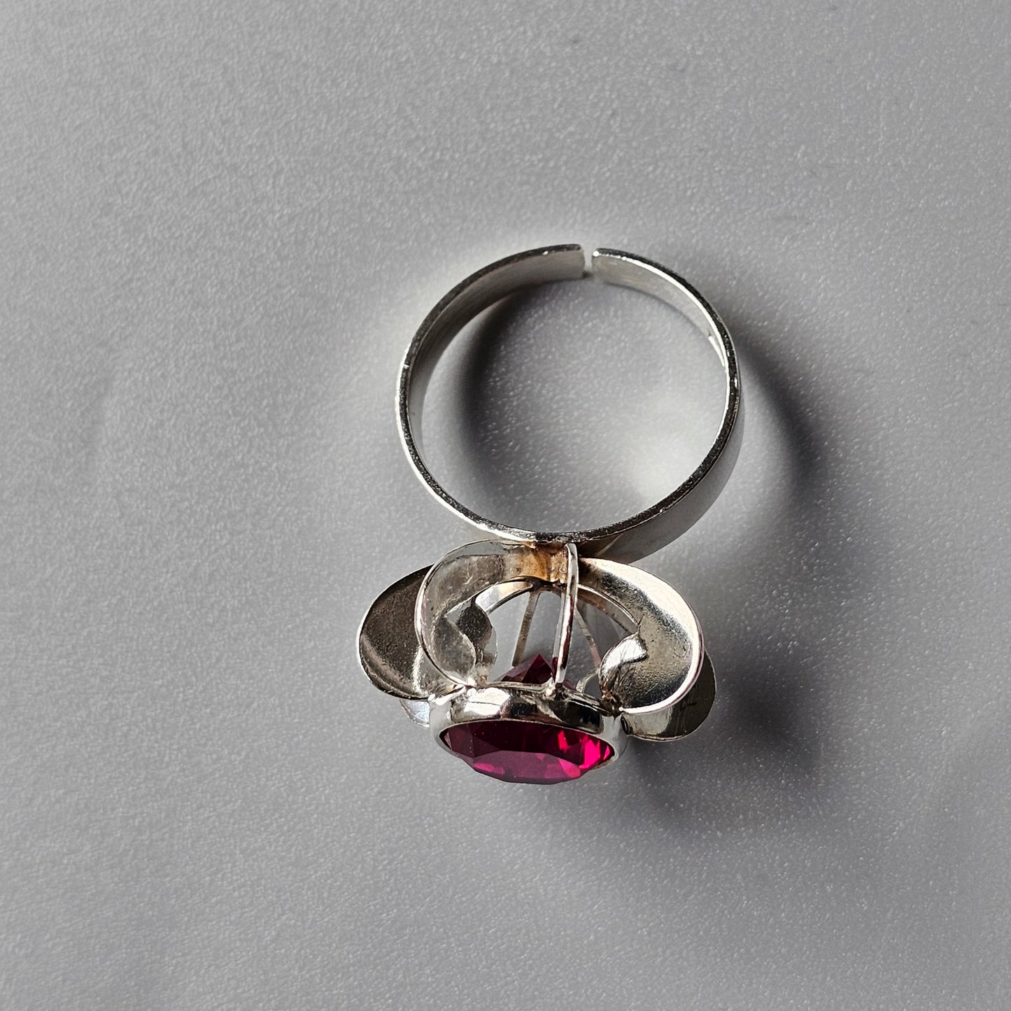 Silver ring with a clear crystal structure holding a red gemstone.