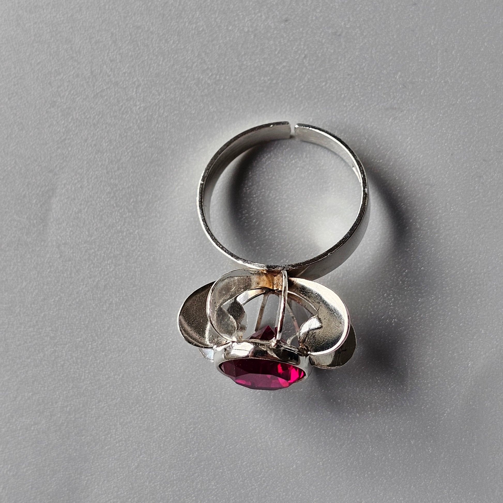 Silver ring with a clear crystal structure holding a red gemstone.