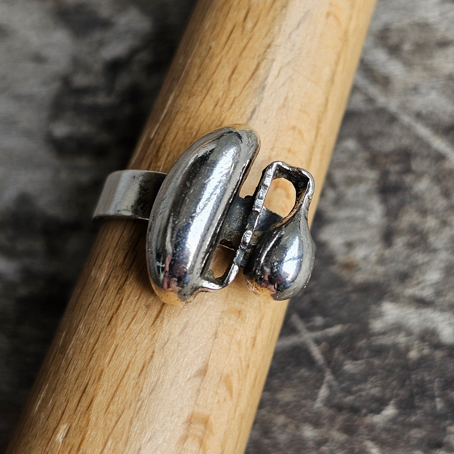 Silver ring with an abstract, curved design resembling two droplets or beans.