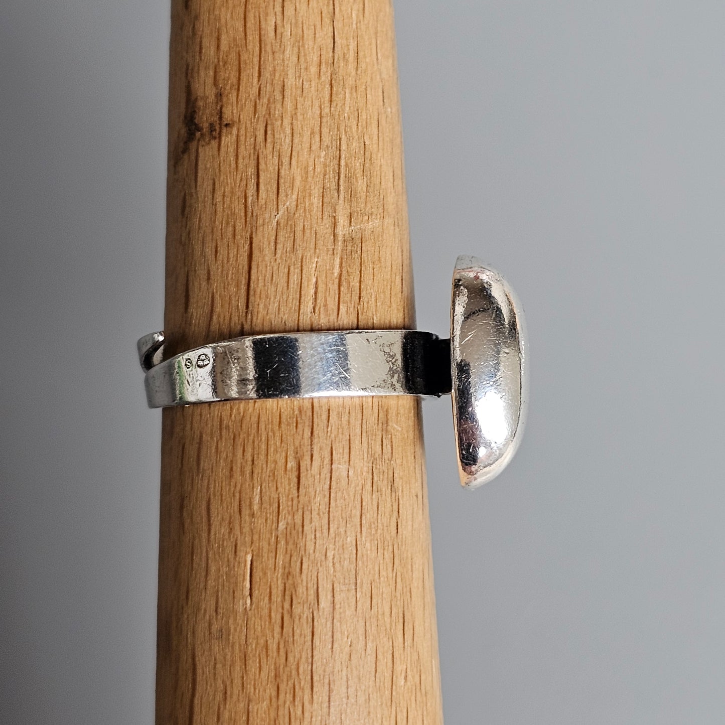 Silver ring with a protruding half-dome shape attached to the band.