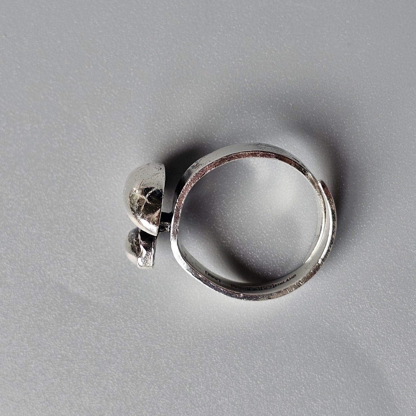 Silver ring with a small skull-shaped charm or decoration attached to the band.