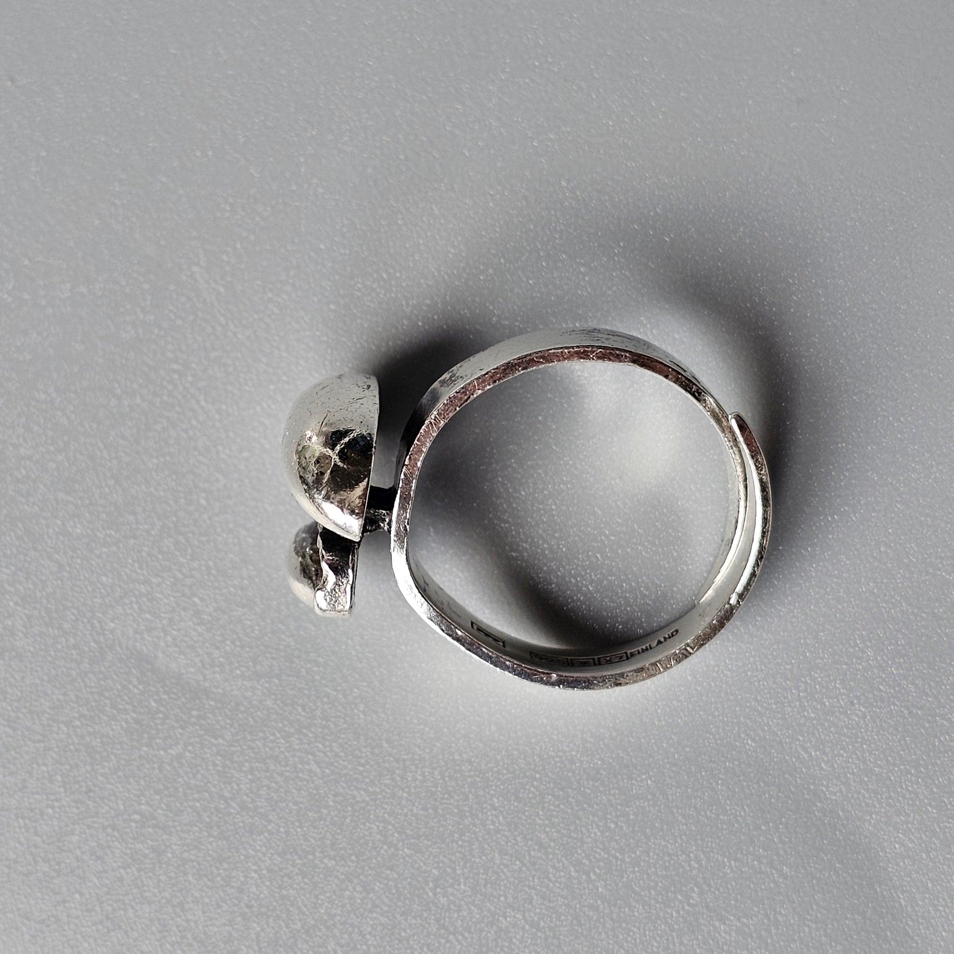 Silver ring with a small skull-shaped charm or decoration attached to the band.