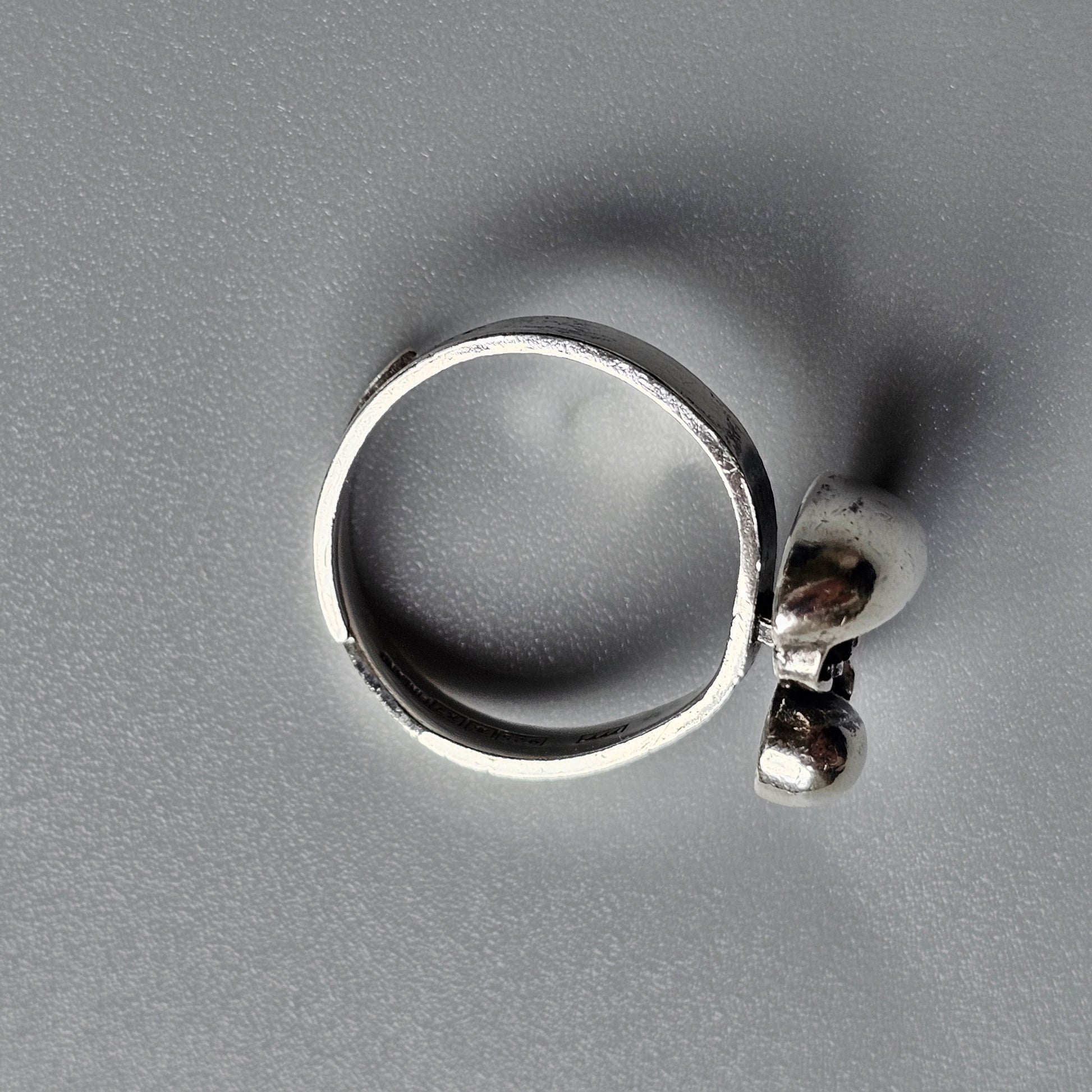 Silver ring with a small decorative attachment resembling a skull.