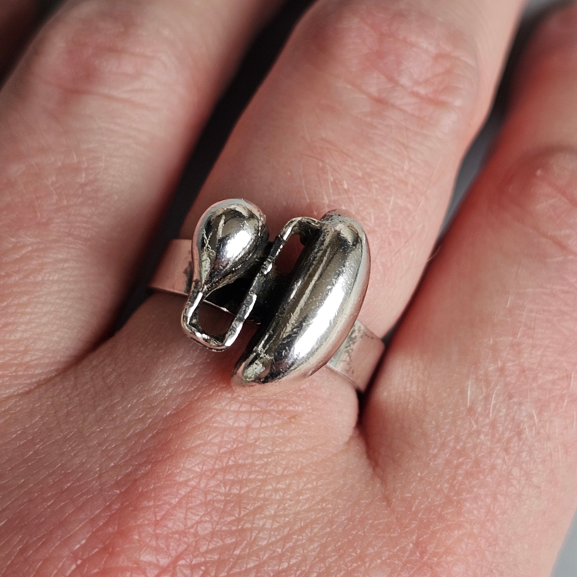 Silver ring shaped like two abstract, curved forms intertwining.