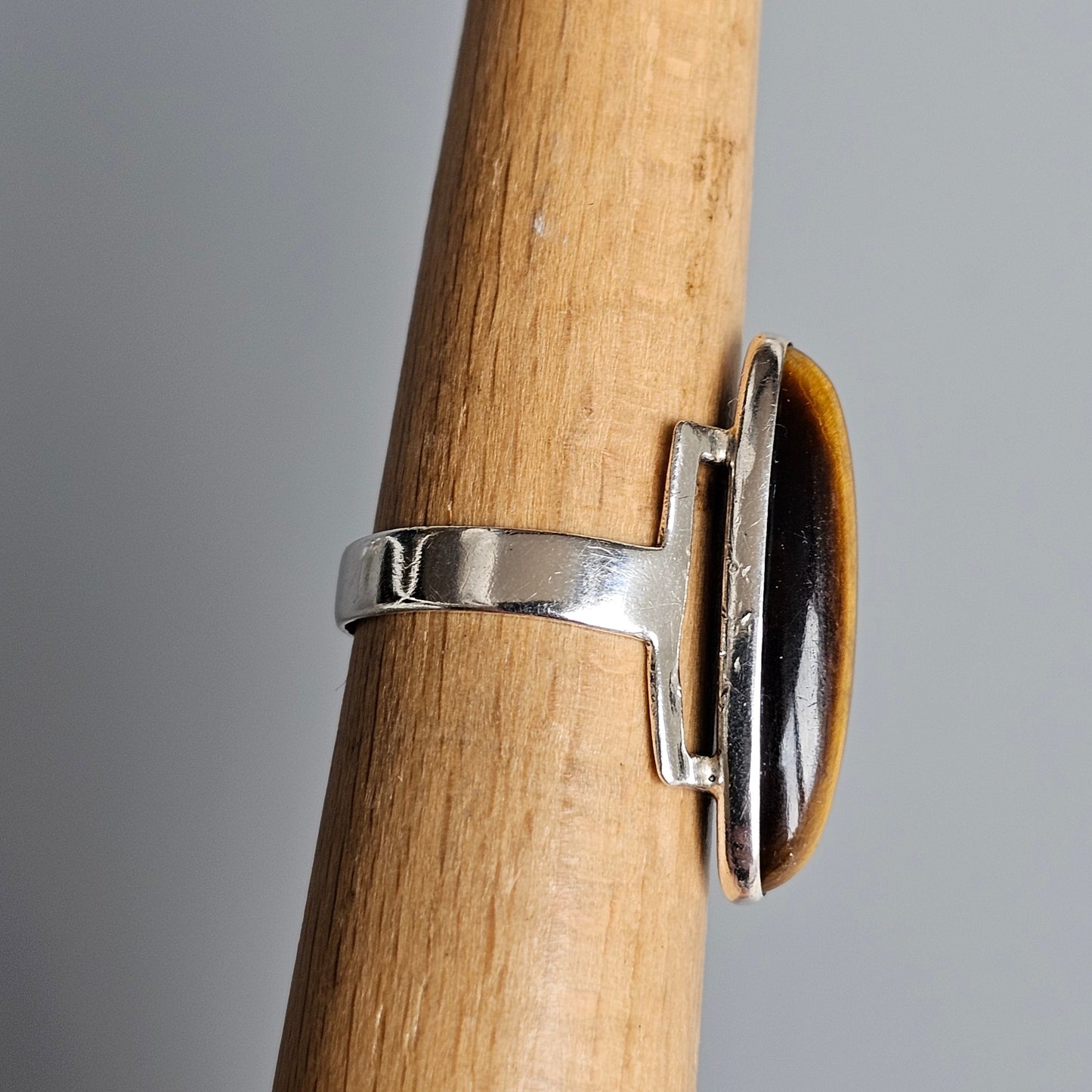 Ring with an oval amber-colored stone set in a silver-toned metal band.