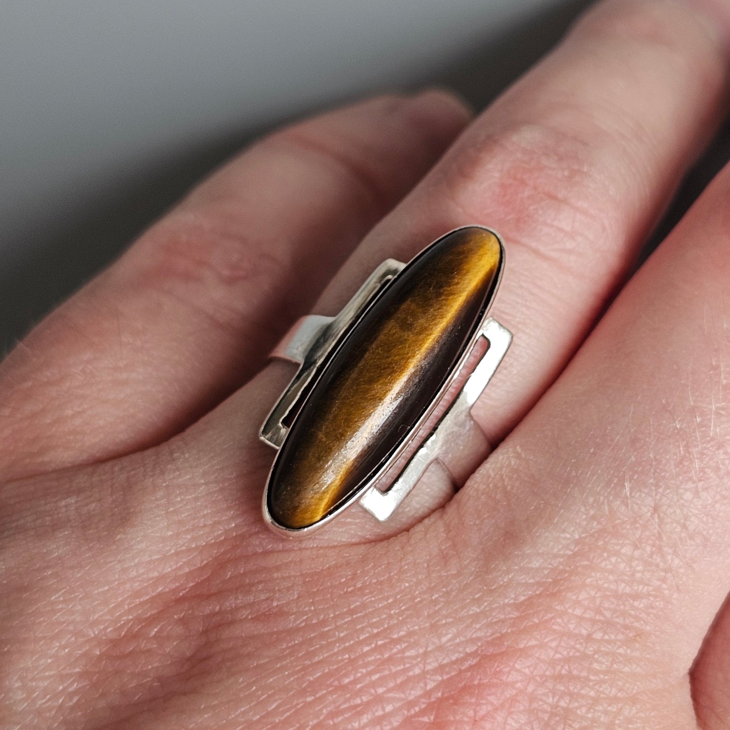 Silver ring with an elongated oval tiger’s eye gemstone.