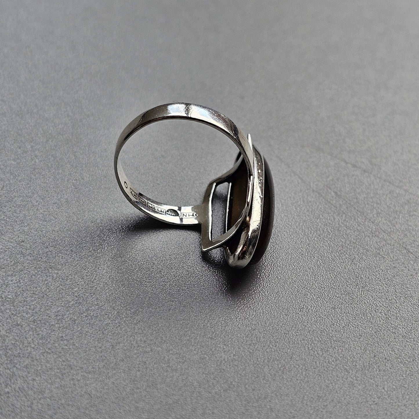 Silver ring with an abstract, curved design element.