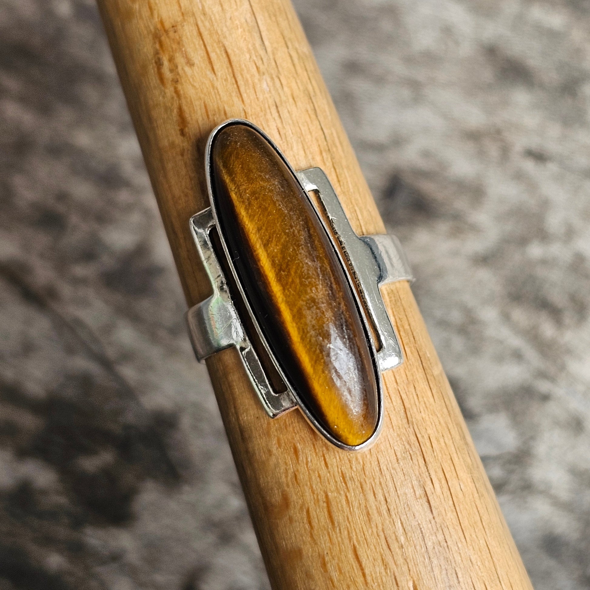 Silver ring with an elongated oval tiger’s eye gemstone.