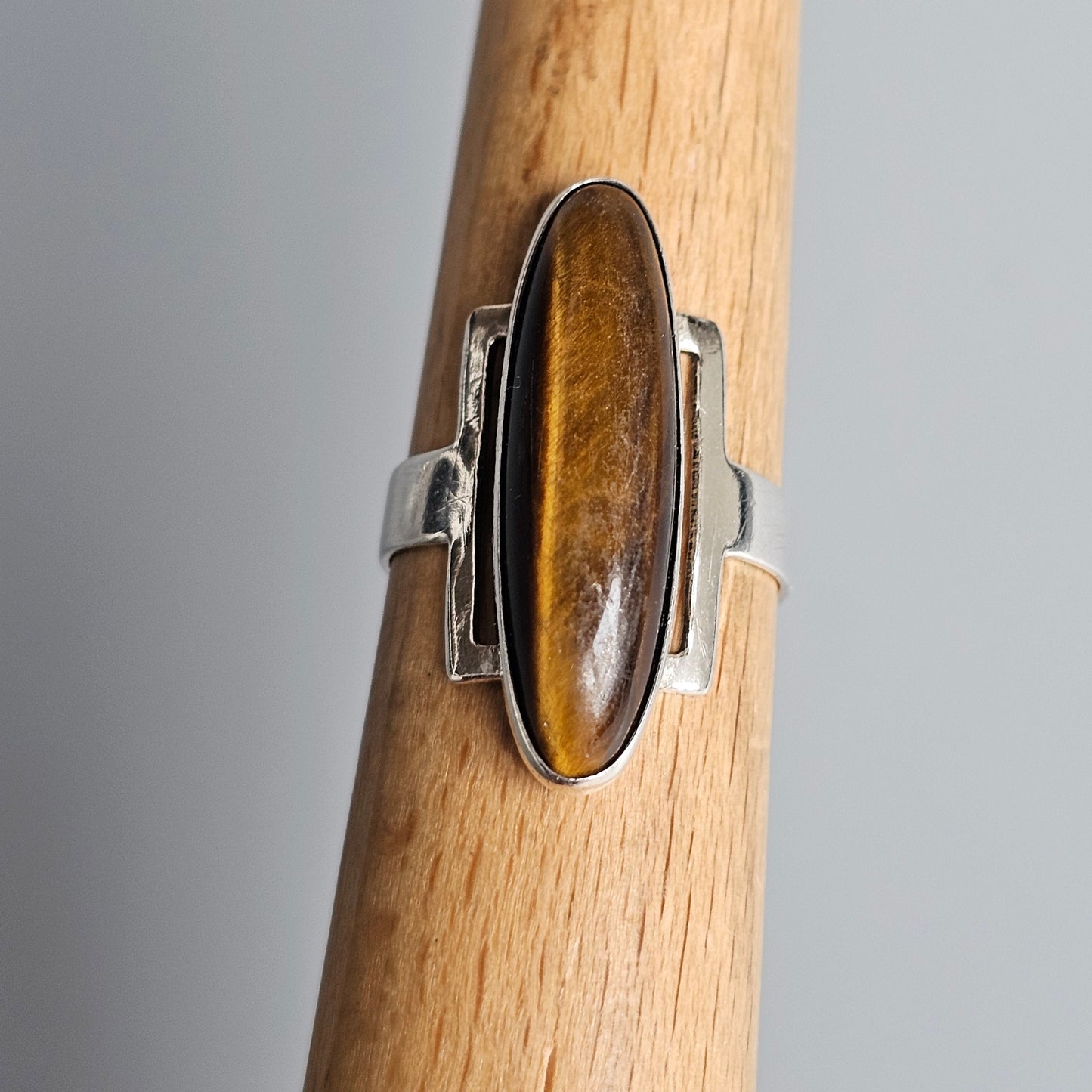 Silver ring with an elongated oval tiger’s eye gemstone.